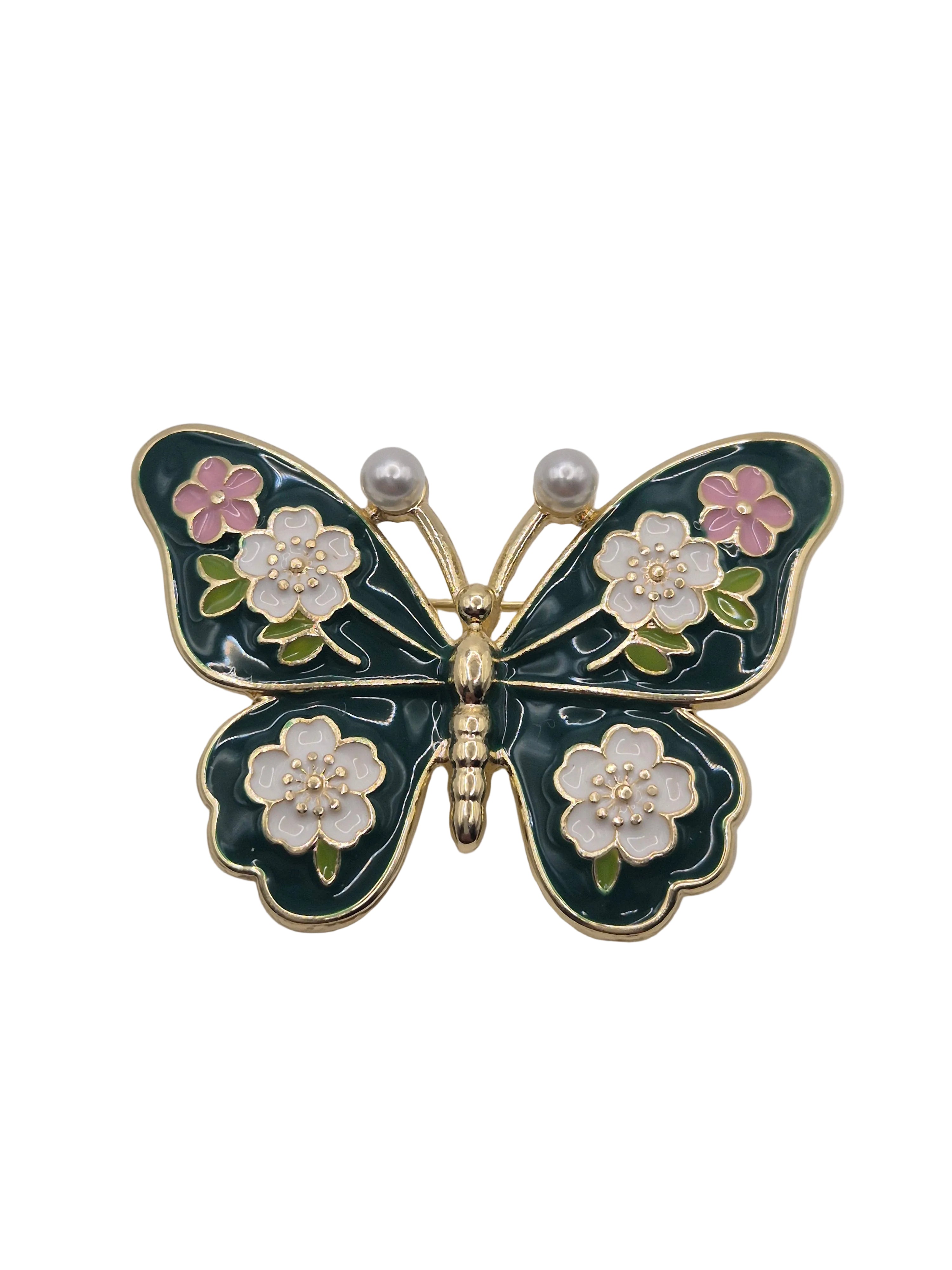 Butterfly-shaped brooch with floral details on a gray background
