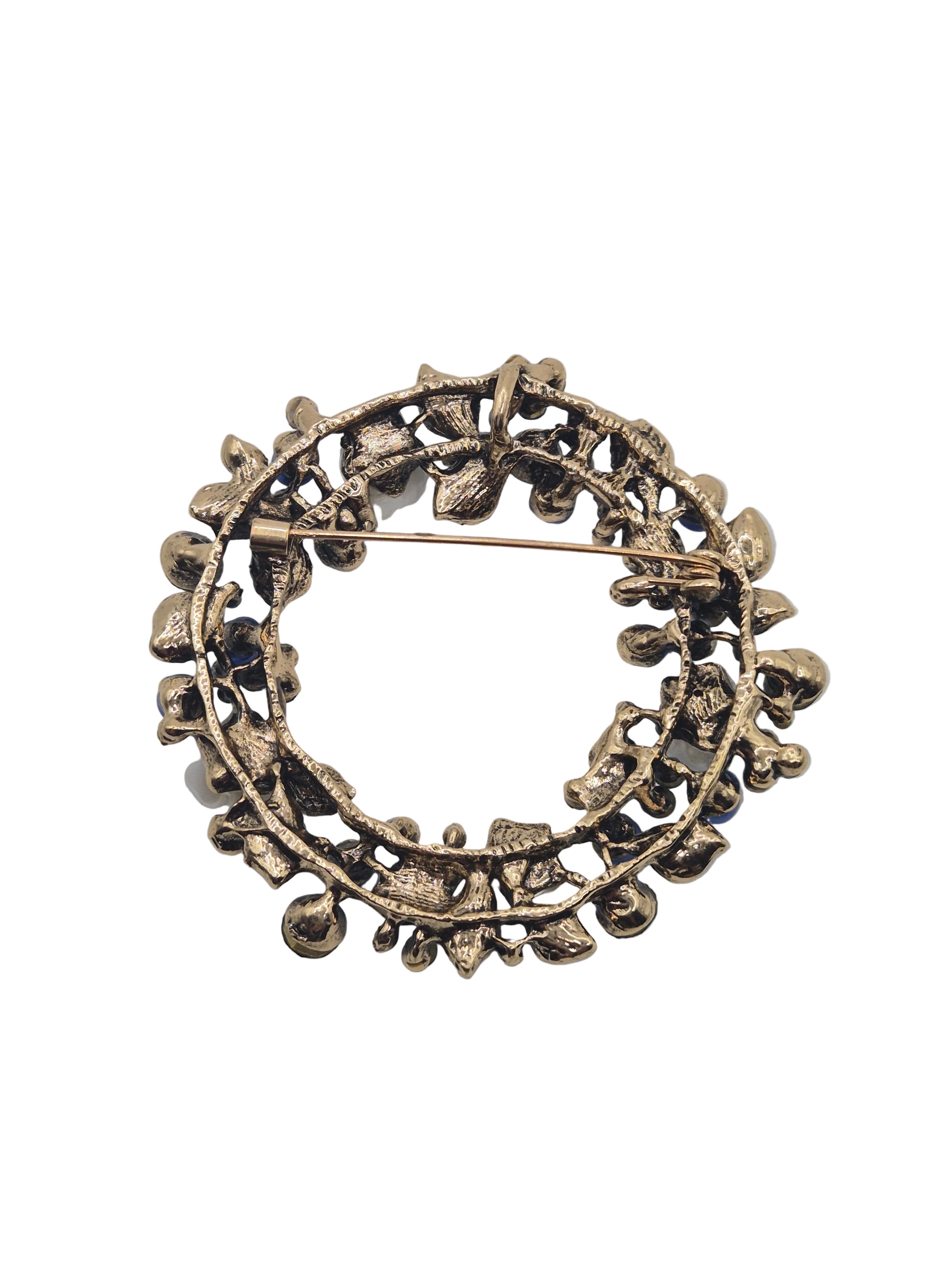 Blue floral brooch with leaf design on a white background