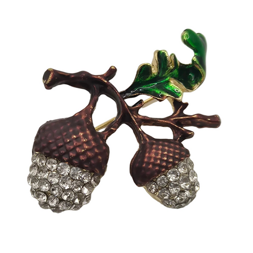 An acorn brooch featuring textured bronze-colored acorns covered with clear rhinestones, brown branches, and glossy green enamel leaves on a gold-tone setting, isolated on a white background.
