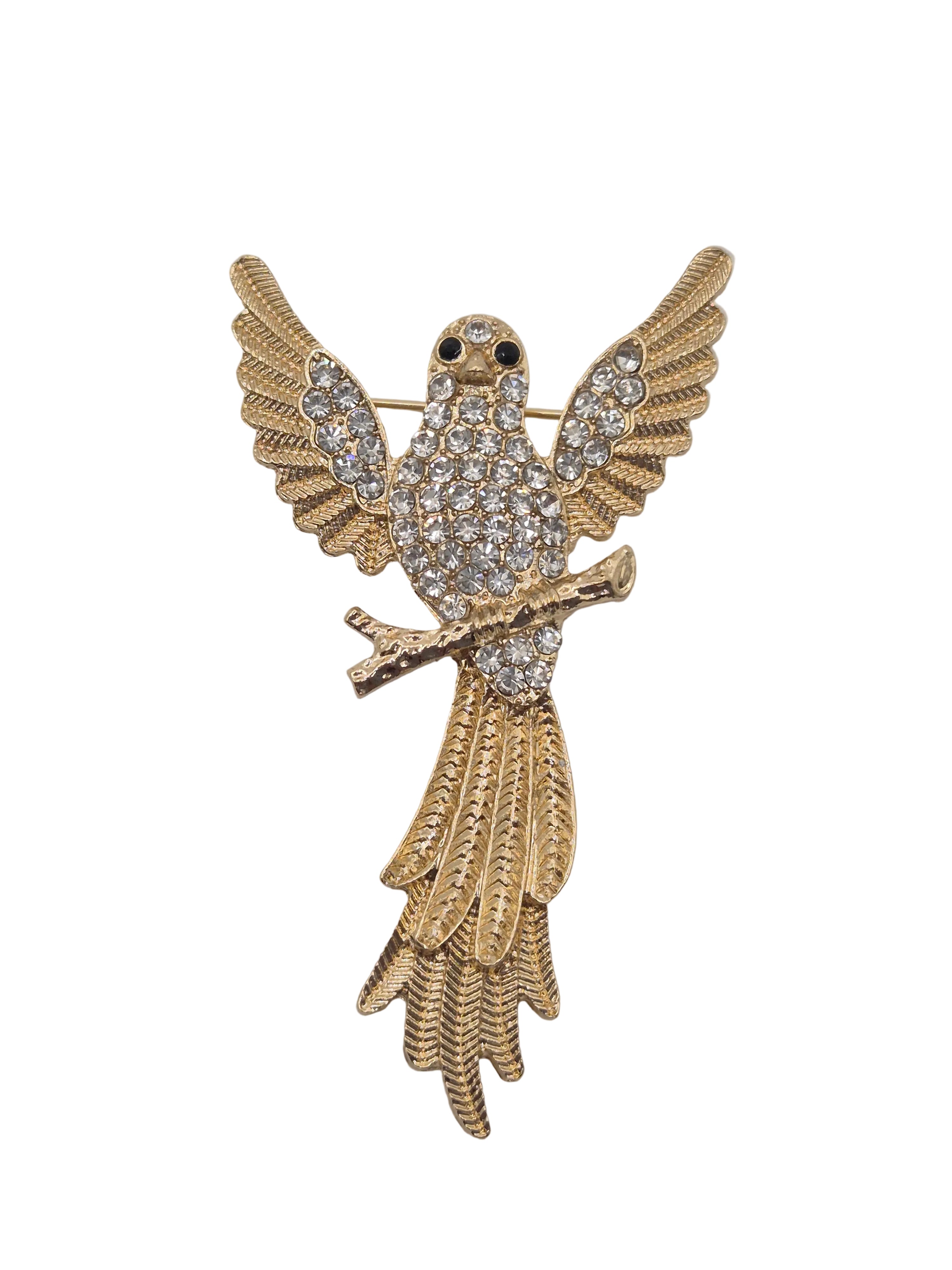 Gold bird brooch with wings spread, embellished with clear rhinestones on the body and tail, set against a plain white background.
