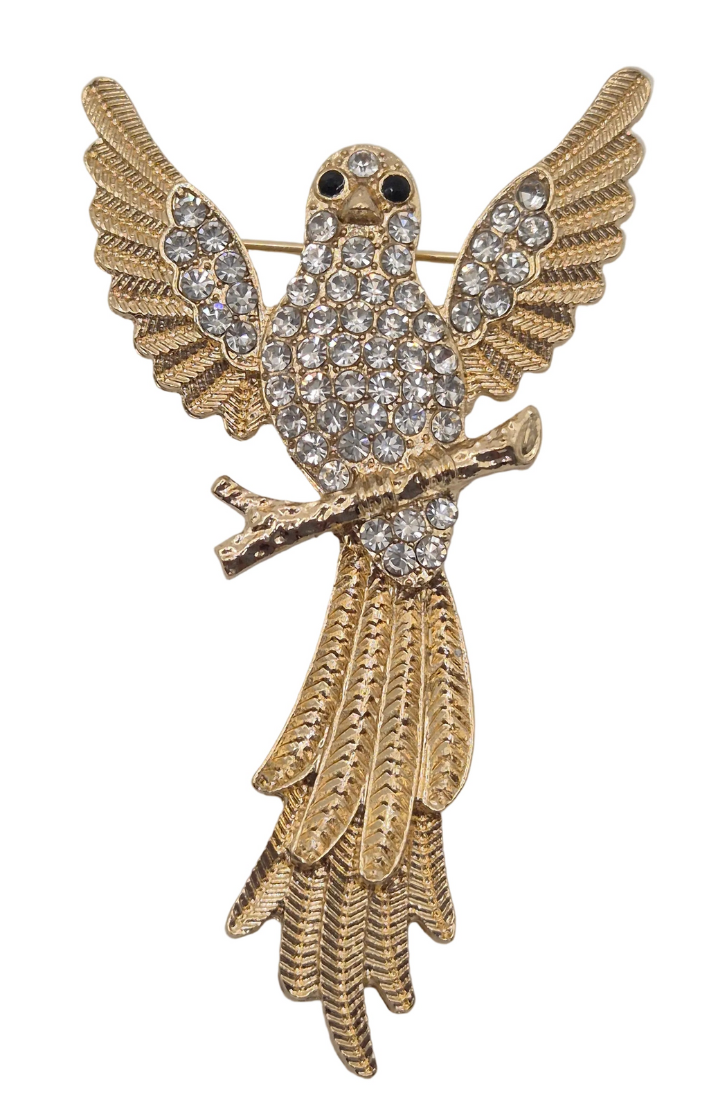 A gold bird brooch with wings spread, covered in clear rhinestones, featuring small black eyes and a branch detail, set against a plain white background.