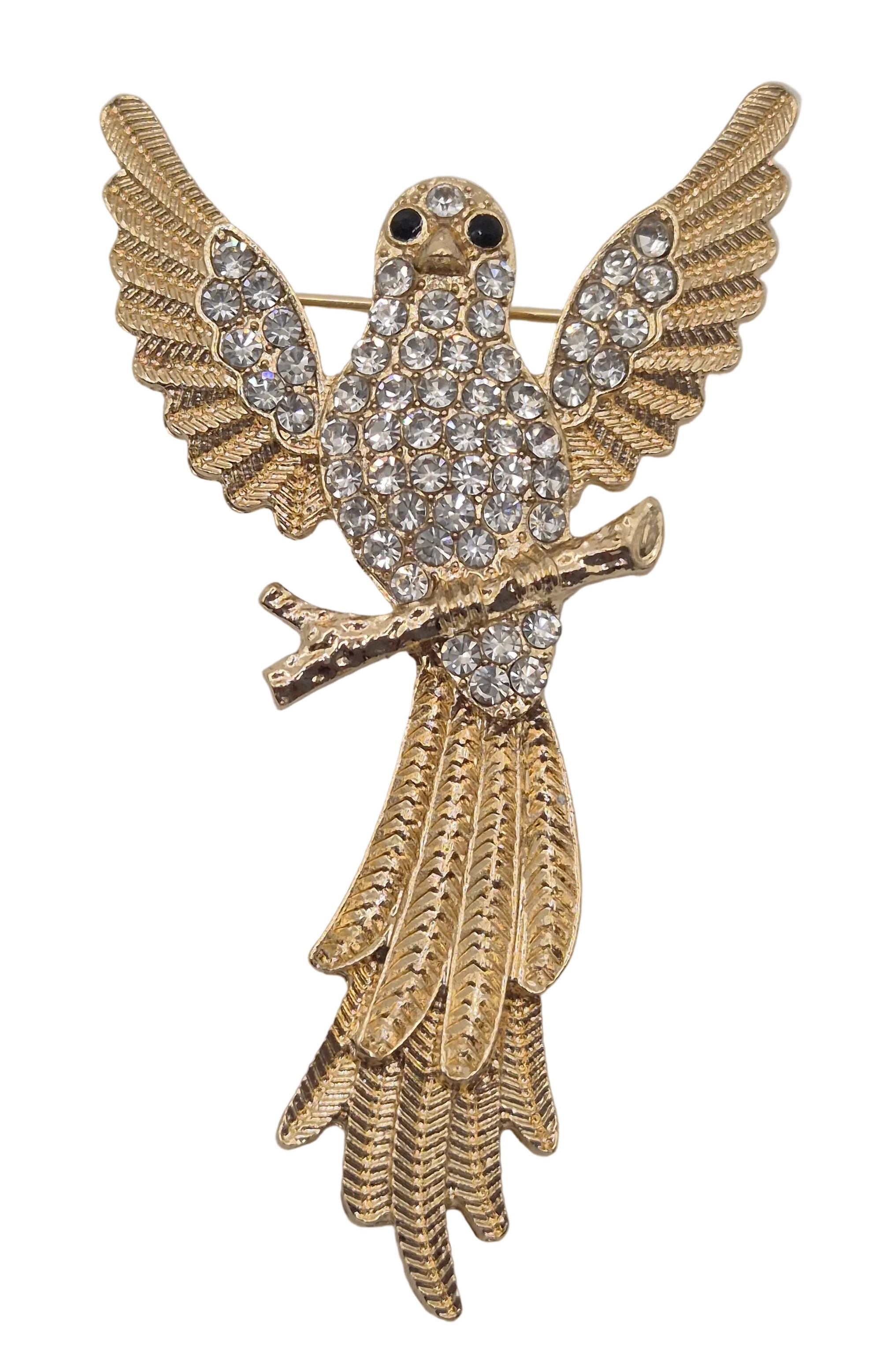 A gold bird brooch with wings spread, covered in clear rhinestones, featuring small black eyes and a branch detail, set against a plain white background.