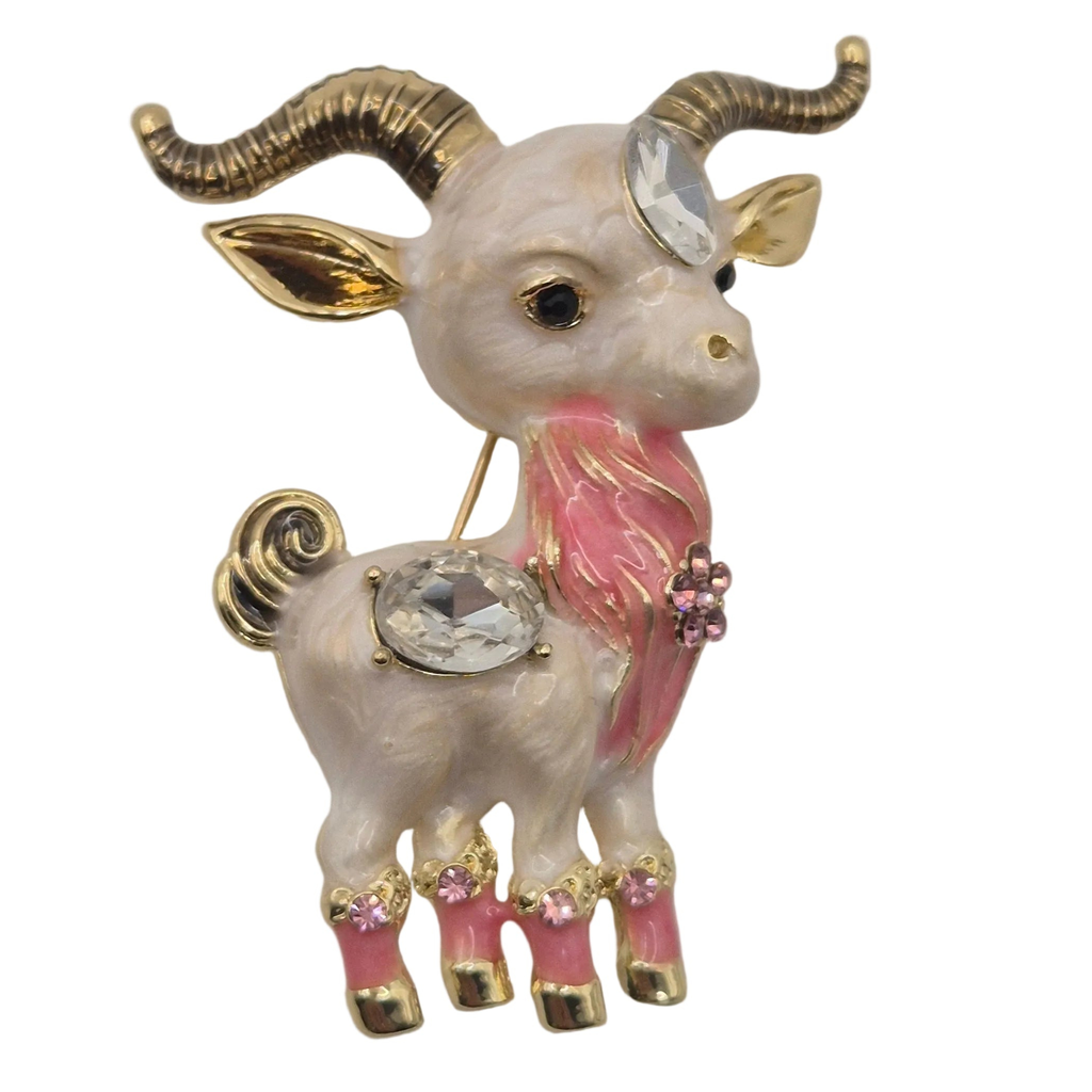 A decorative ram brooch with gold-tone metal, pink enamel accents, and clear rhinestones, shown on a plain white background.