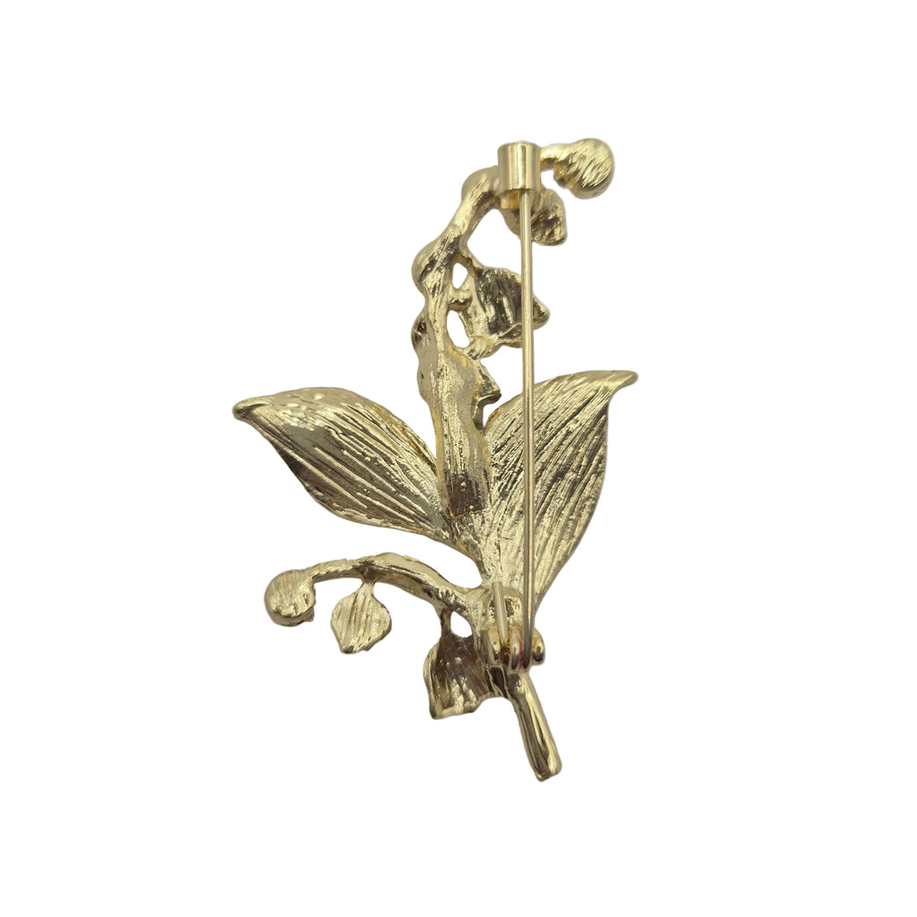 Reverse gold tone side of a lily of the valley brooch, photographed on a plain white background.