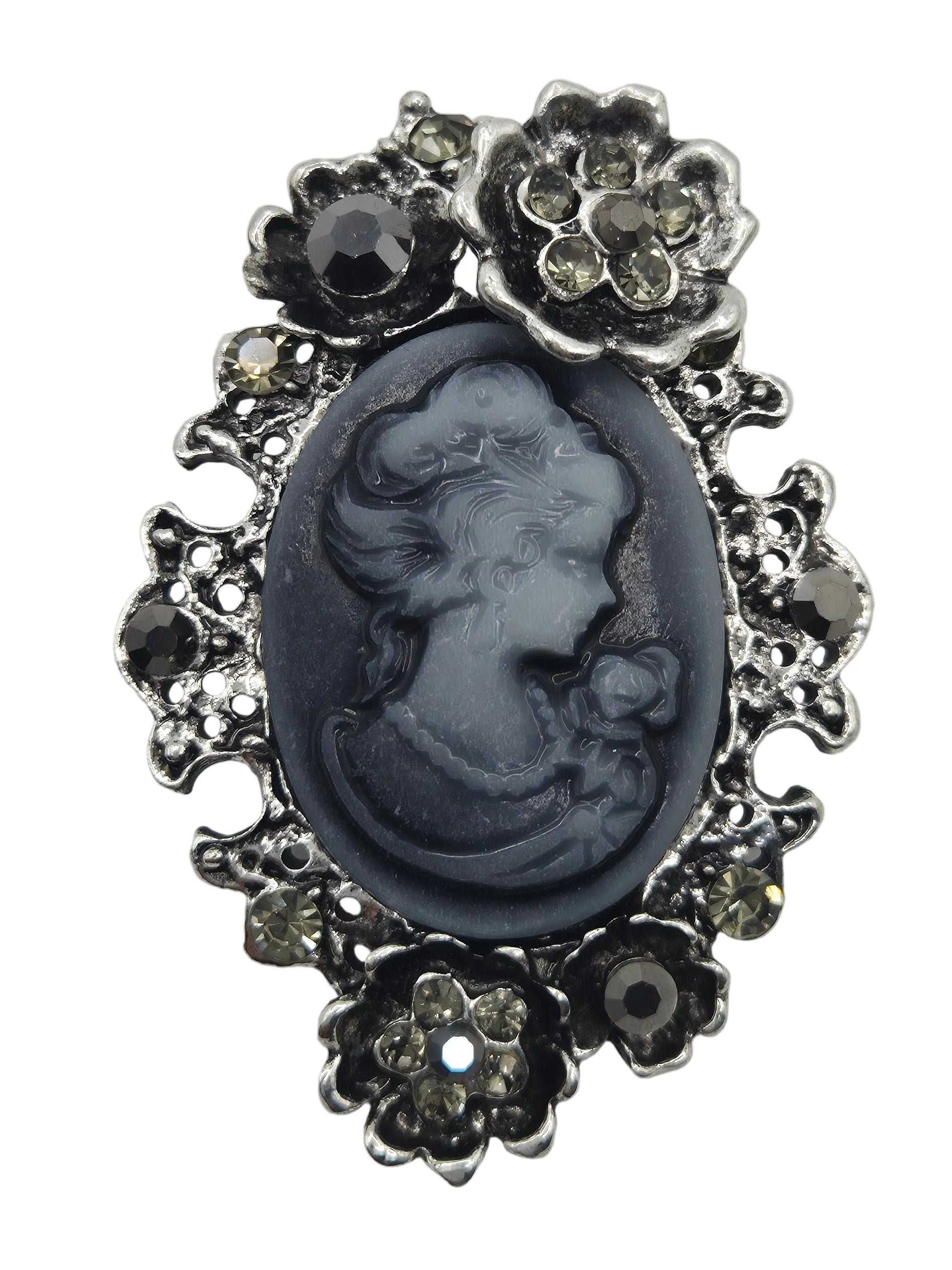 A vintage-style cameo brooch featuring a dark gray carved oval portrait in the center, surrounded by an ornate silver-tone floral border with small clear rhinestone accents, set against a plain white background.