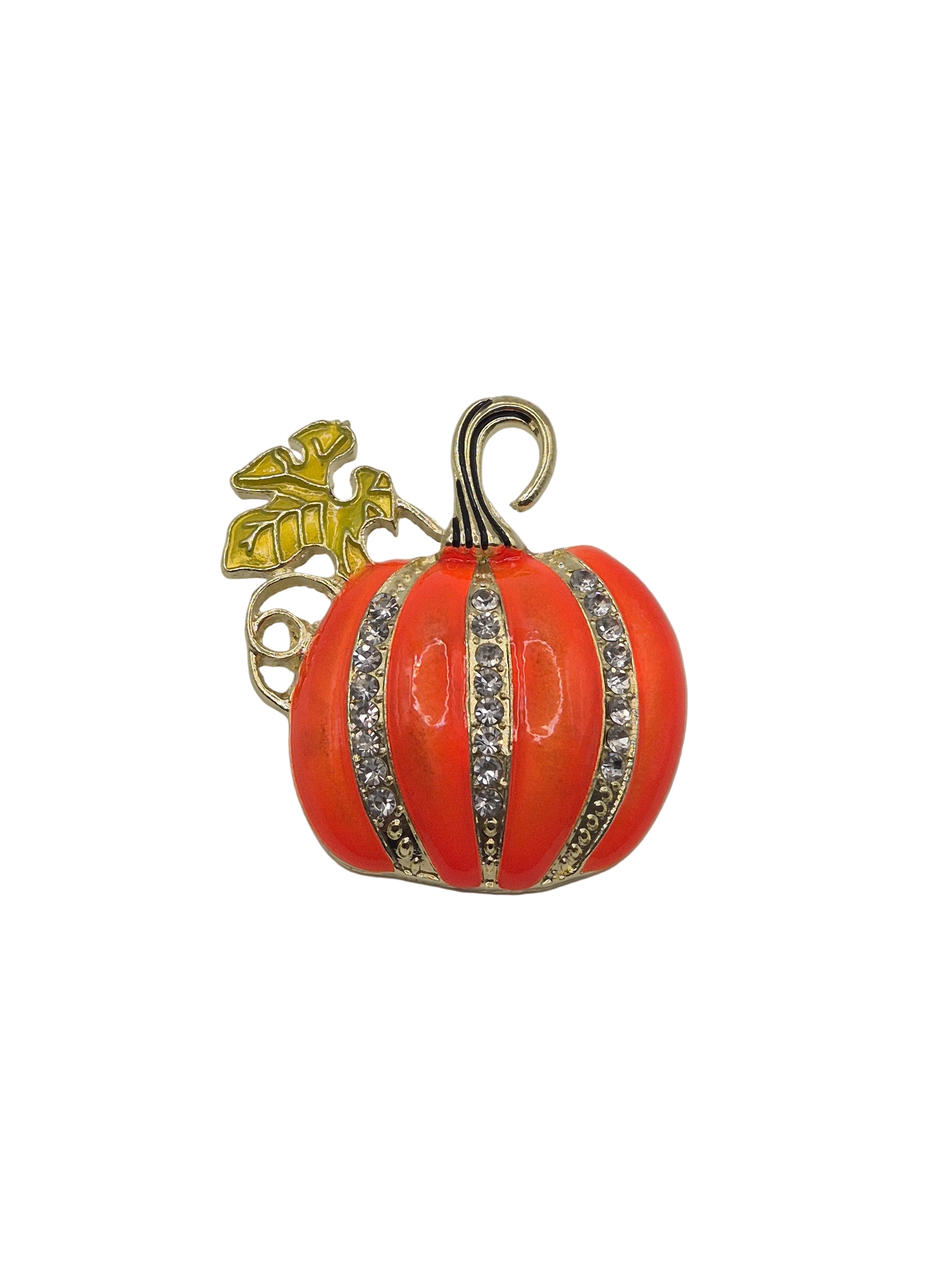 An orange enamel pumpkin booch with gold-toned metal detailing, including a stem, bail, and vertical stripes embellished with clear rhinestones.