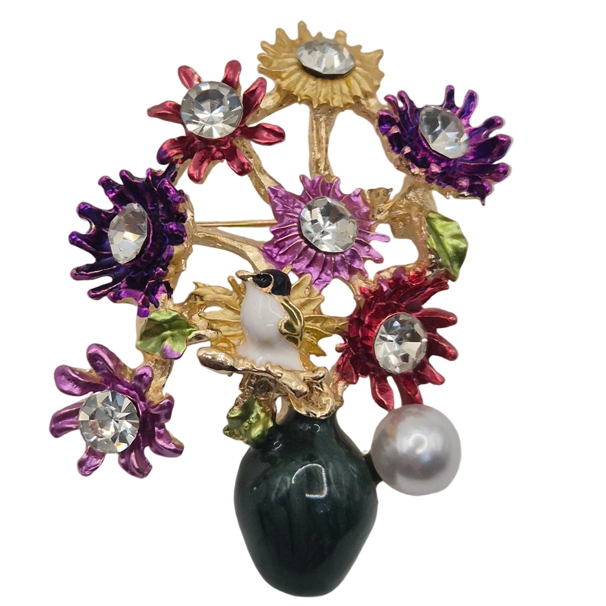 A colorful floral brooch featuring gold-tone metal, purple and red enamel flowers, clear rhinestones, a white pearl, and a dark green pear-shaped accent, set against a plain white background.
