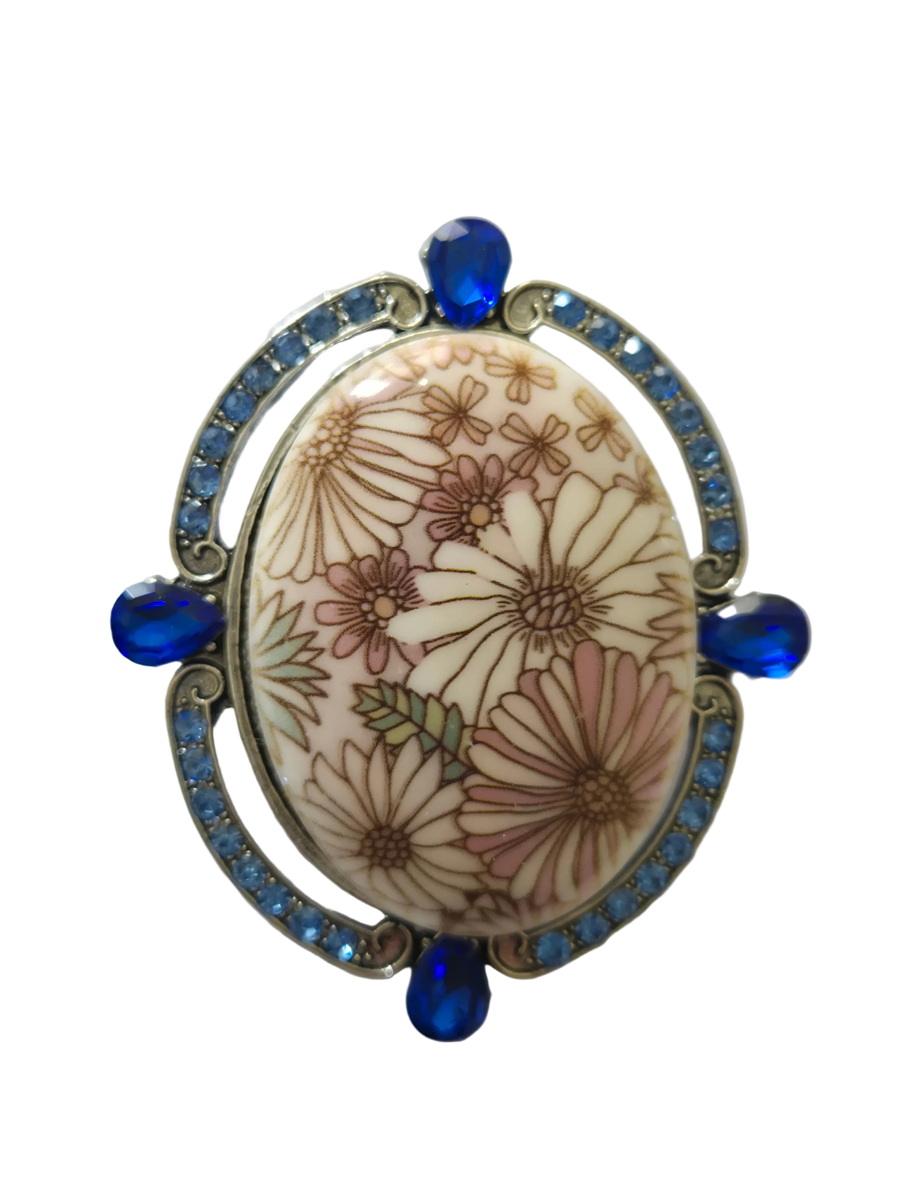 Decorative brooch with floral design and blue accents on a white background