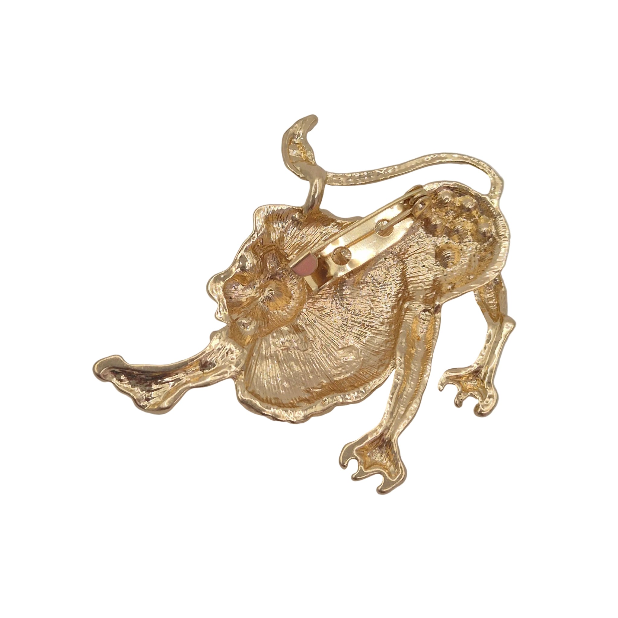 A gold lion-shaped brooch with a textured, organic surface and a visible metal clasp on the side, photographed on a plain light gray background.
