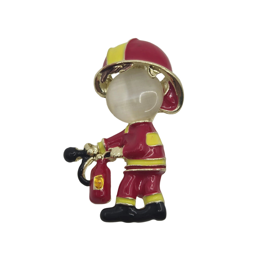 A firefighter-themed enamel pin or brooch featuring a small cartoon-style figure in a red helmet and uniform with yellow reflective stripes, holding a red fire extinguisher, set against a plain white background.