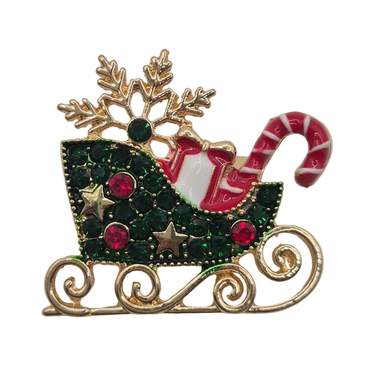 A Christmas-themed gold-tone enamel lapel pin depicting a sleigh filled with red and white striped candy canes, green glitter, and pink rhinestones, with a gold snowflake on top, set against a plain white background.