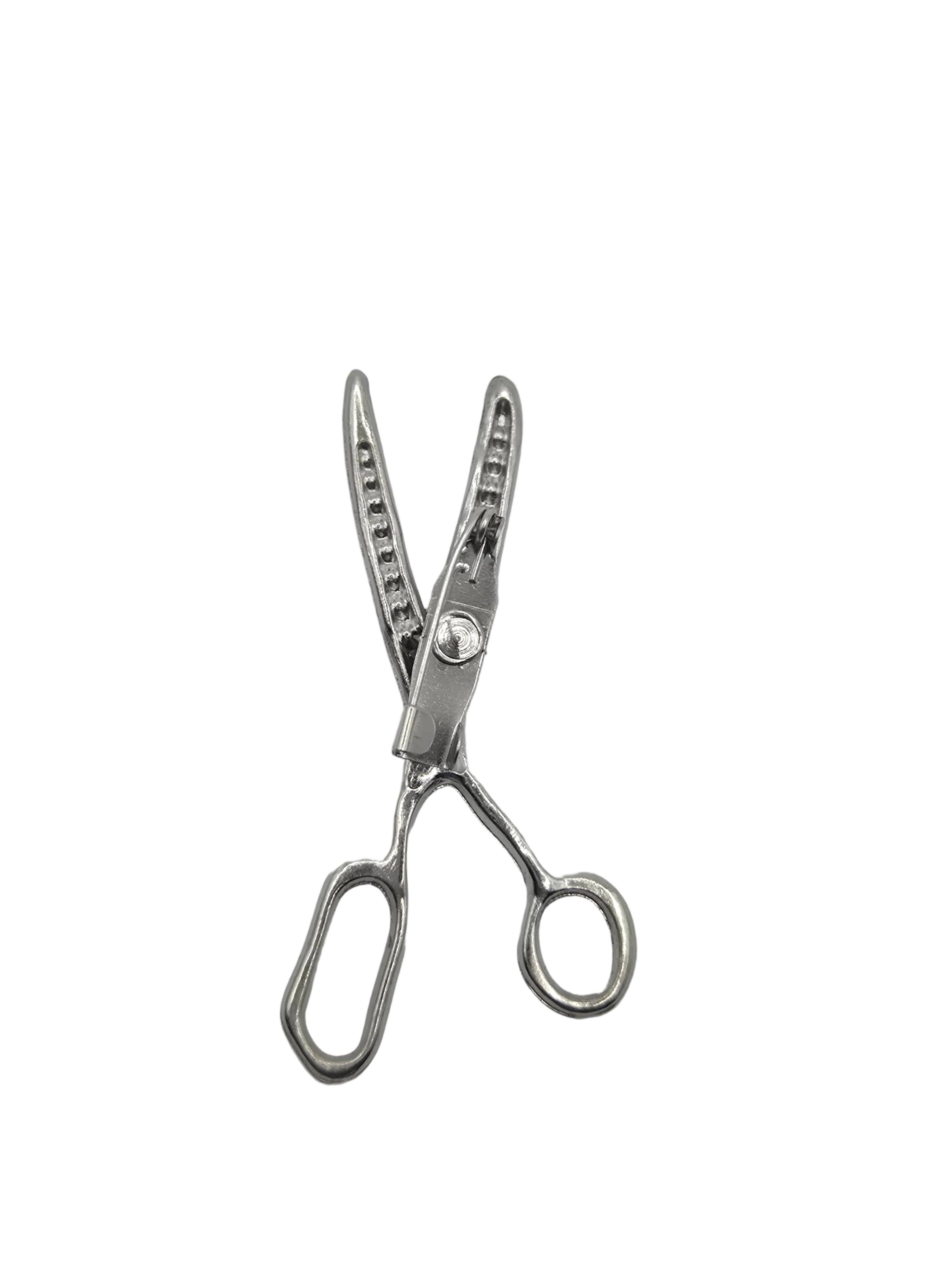 Pair of silver scissors brooch on a gray background