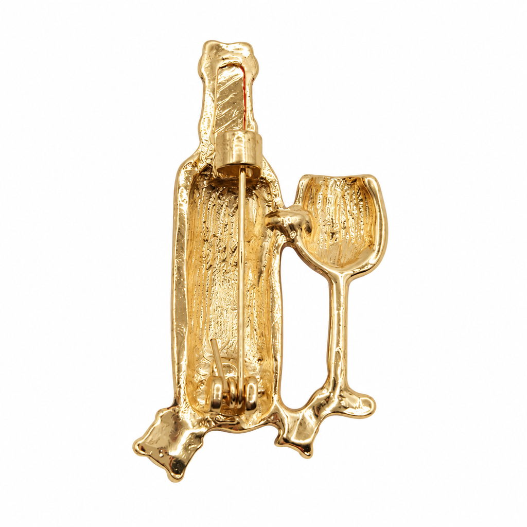 A gold-tone metal pin shaped like a champagne bottle with a clinking wine glass, shown against a plain white background.