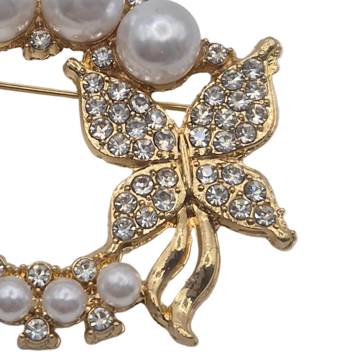 Gold butterfly brooch embellished with clear rhinestones and accented with white faux pearls, shown on a plain white background.