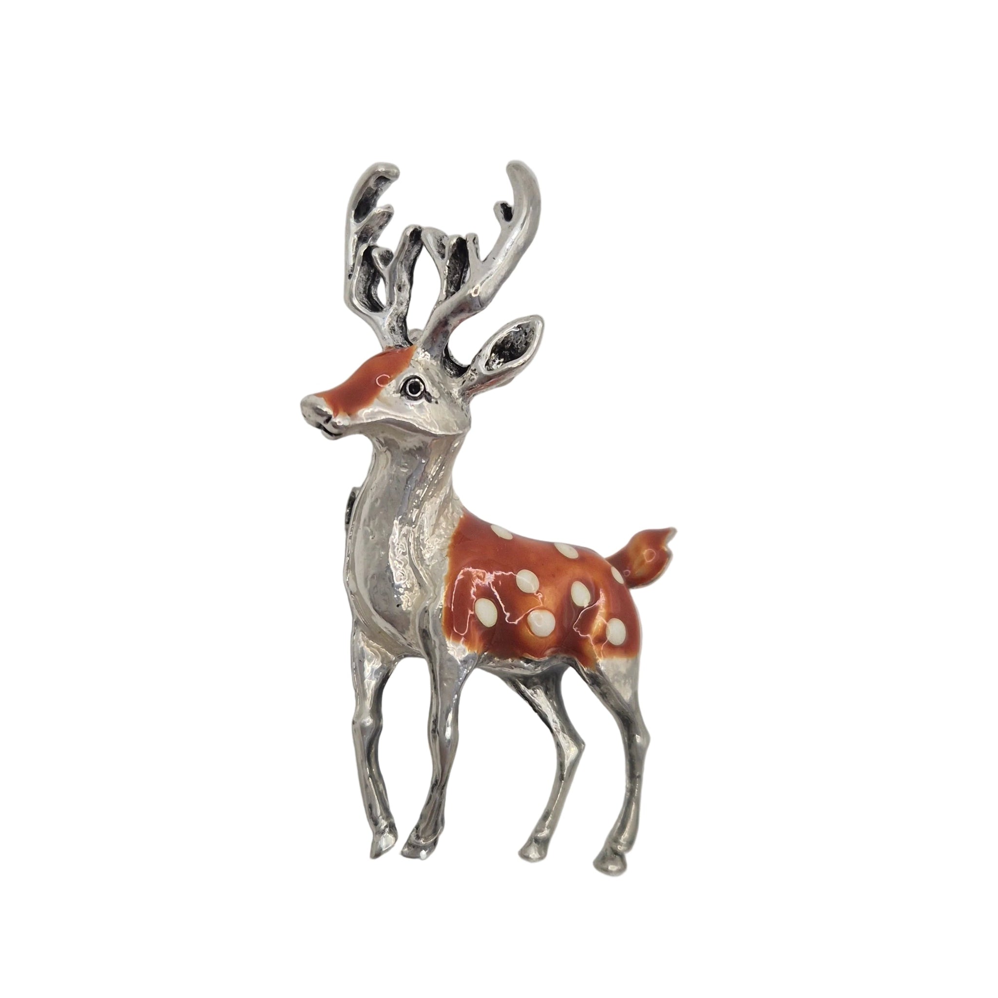 A small deer-shaped brooch or pin with a silver-toned body and antlers, decorated with orange-red enamel and white spots, shown on a plain light background.