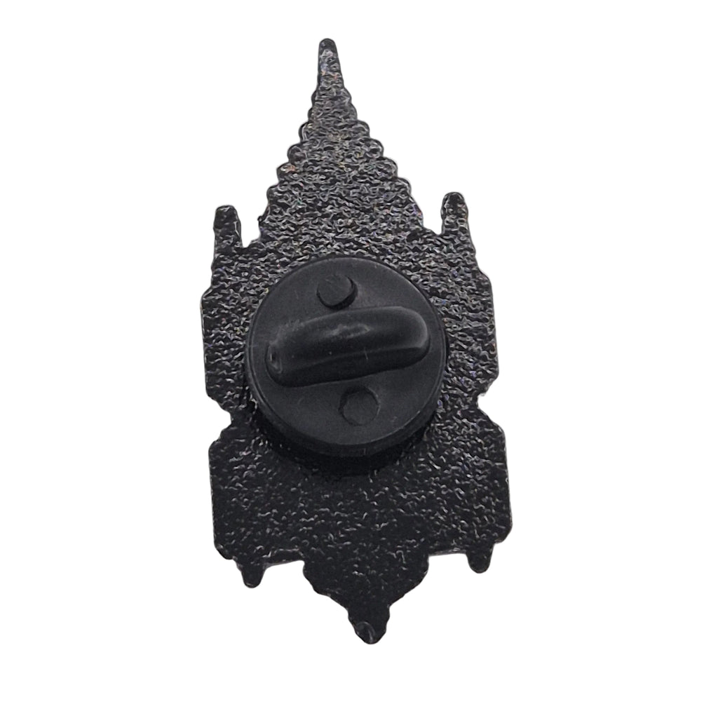 A black textured metal badge or pin shaped like a pointed spire, with a circular black clasp or hook in the center, shown on a plain white background.
