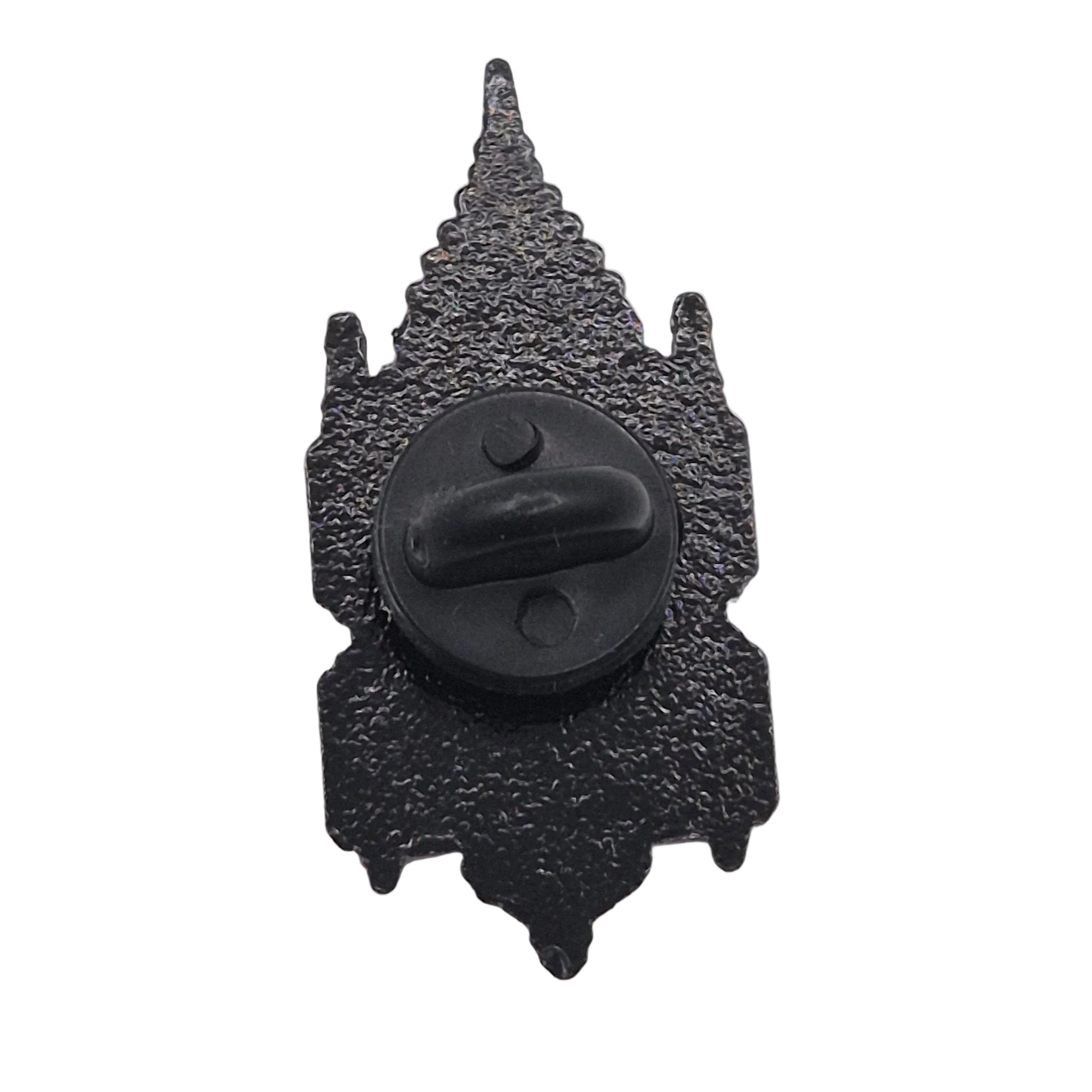 A black textured metal badge or pin shaped like a pointed spire, with a circular black clasp or hook in the center, shown on a plain white background.