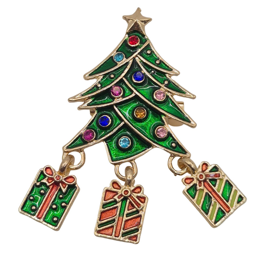 A Christmas tree-shaped brooch with a gold-tone metal outline, green enamel fill, and small multicolored rhinestone accents, with three dangling gift box charms below on a plain white background.