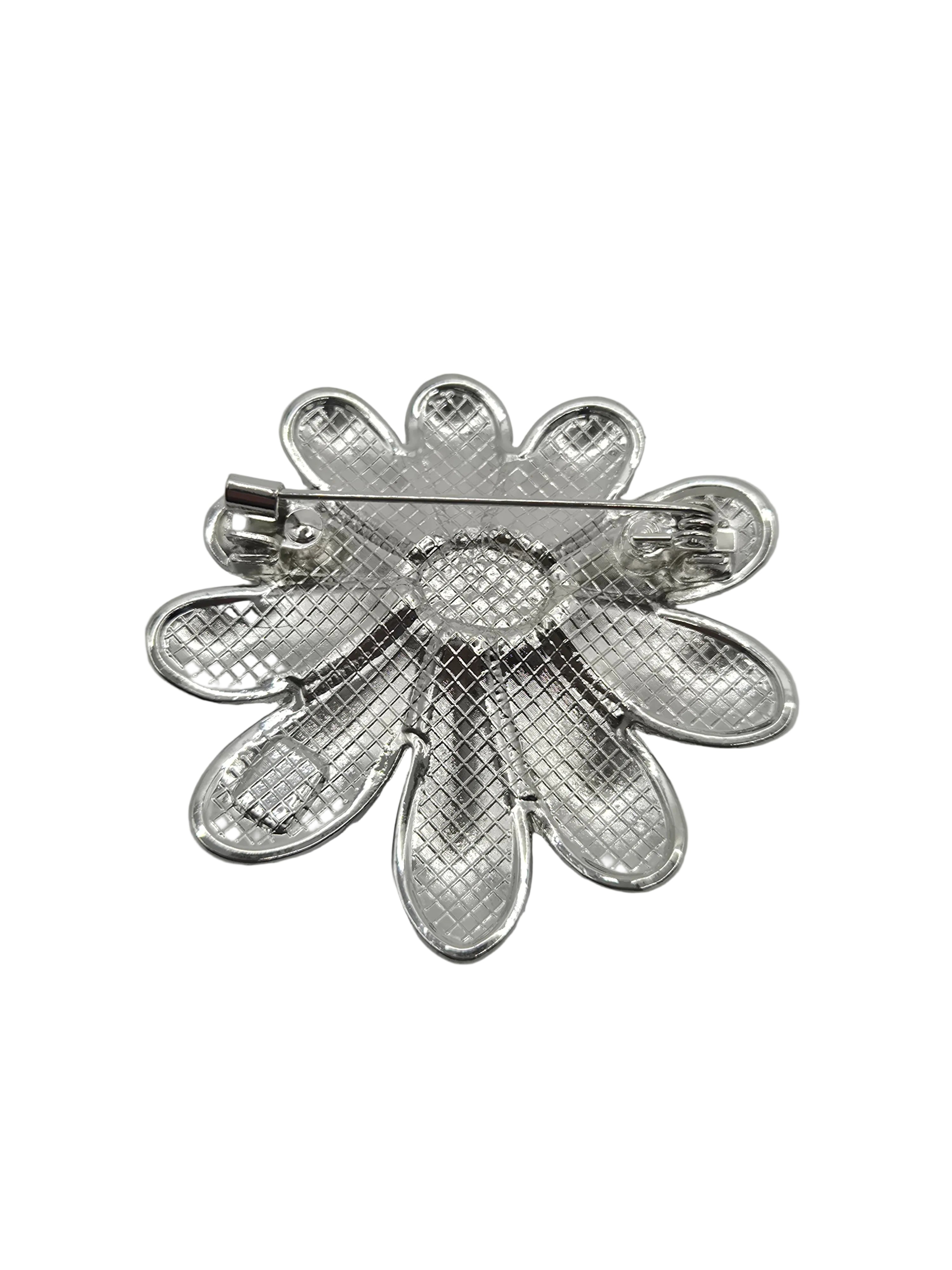 Silver flower-shaped brooch on a gray background
