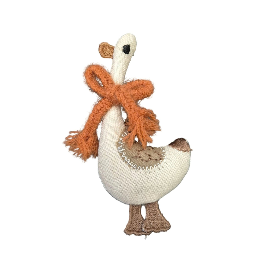 A fabric goose brooch pin with a cream-colored body, orange scarf, and brown accents, isolated on a white background.