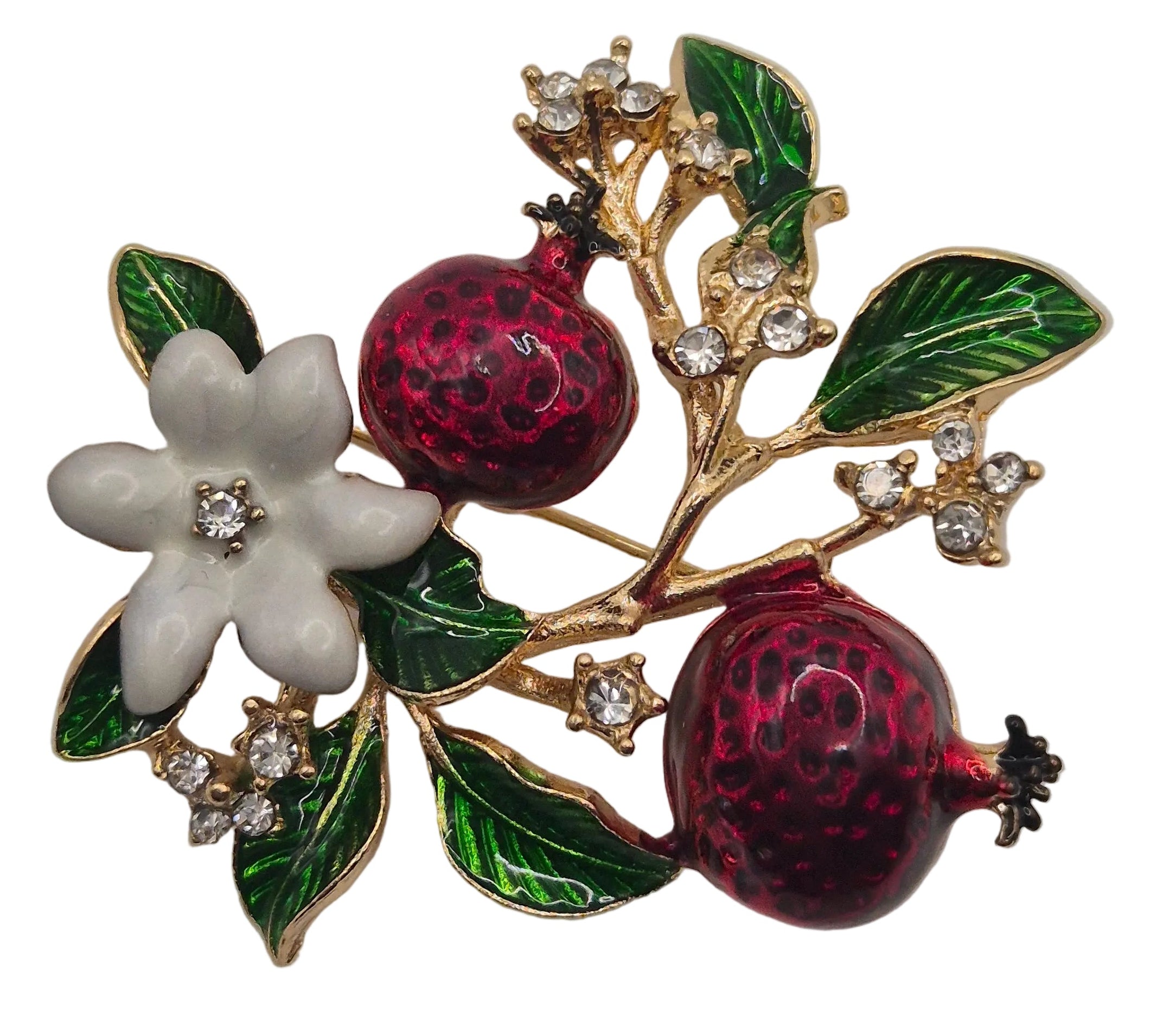 A gold-tone enamel brooch featuring two dark red pomegranate fruits, green leaves, and a white flower with a clear center stone, set against a plain white background.