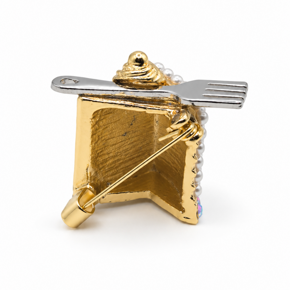 Rear view of cake slice brooch showing the gold-tone back and bar pin fastening.