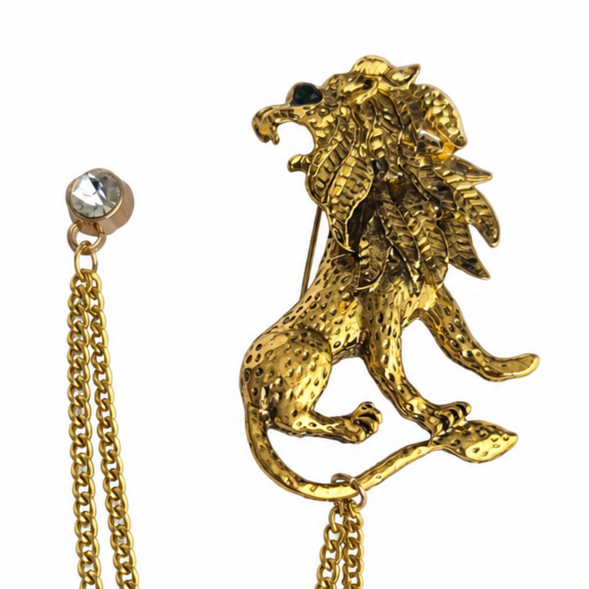 A gold-tone lion brooch with a textured finish, featuring a small dark green eye and a matching gold chain with a clear rhinestone stud, shown on a plain white background.