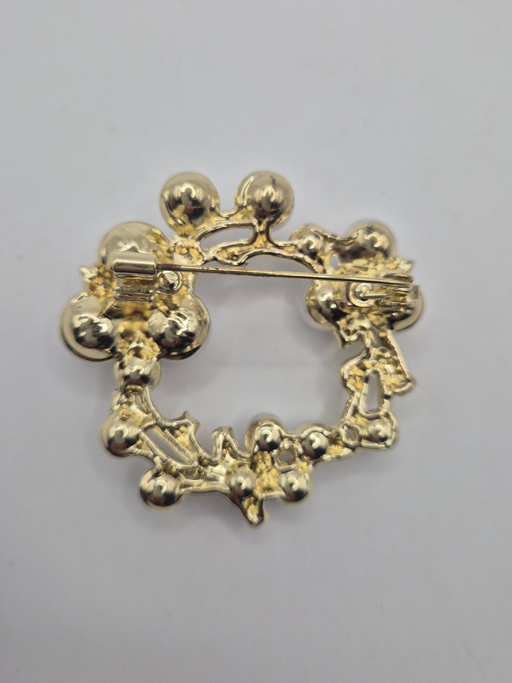 Gold pearl brooch with floral design on a gray background