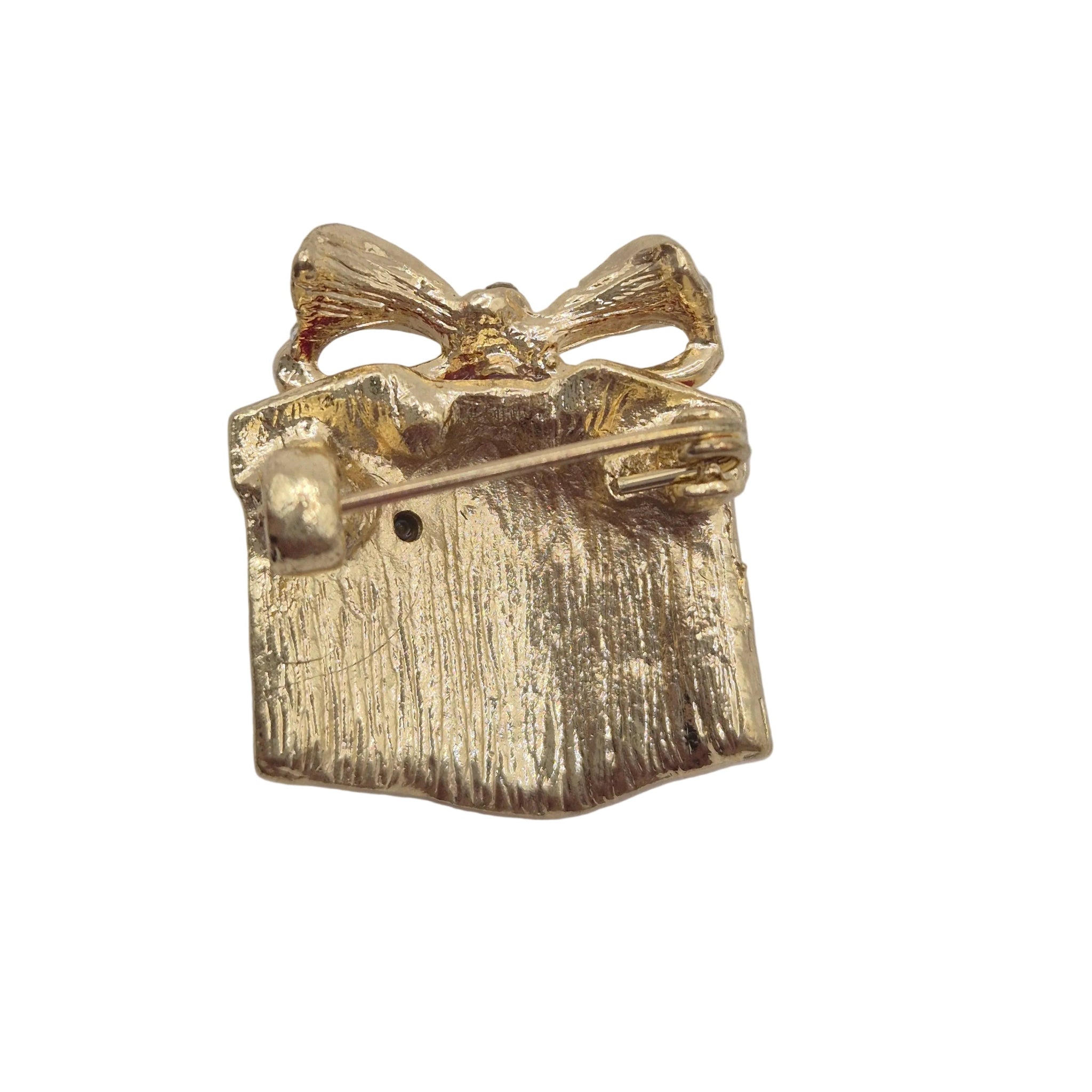 A small gold gift box brooch with a textured finish and ribbon detail, photographed on a plain white background.