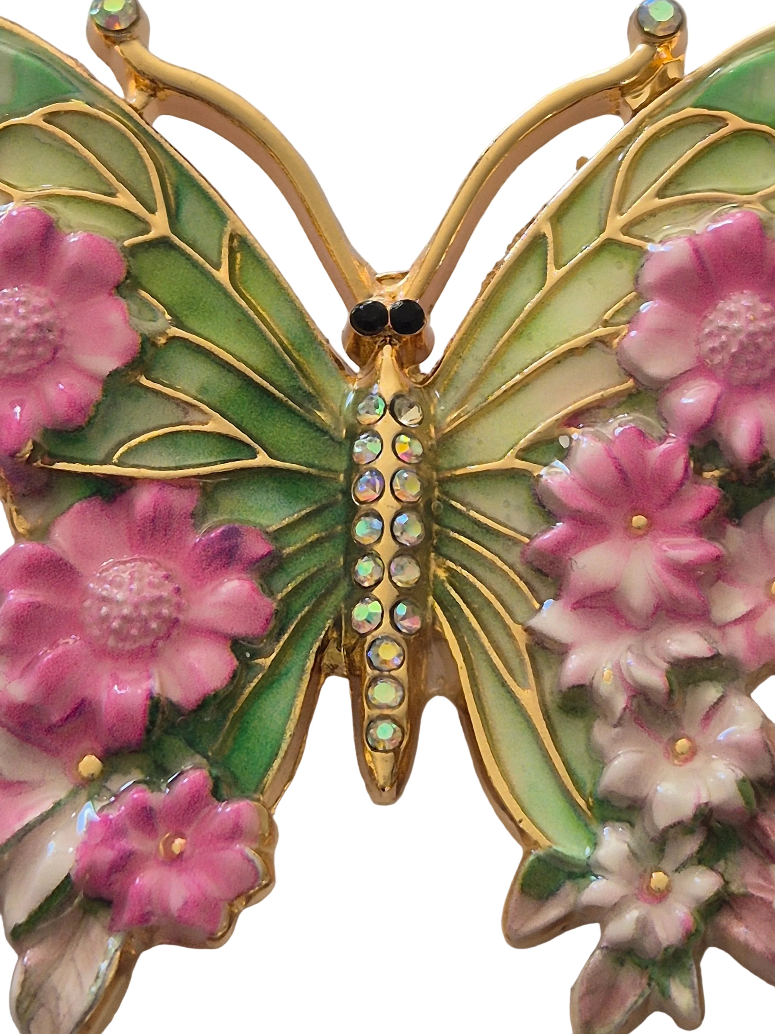 Butterfly brooch with pink flowers and gold accents on a white background