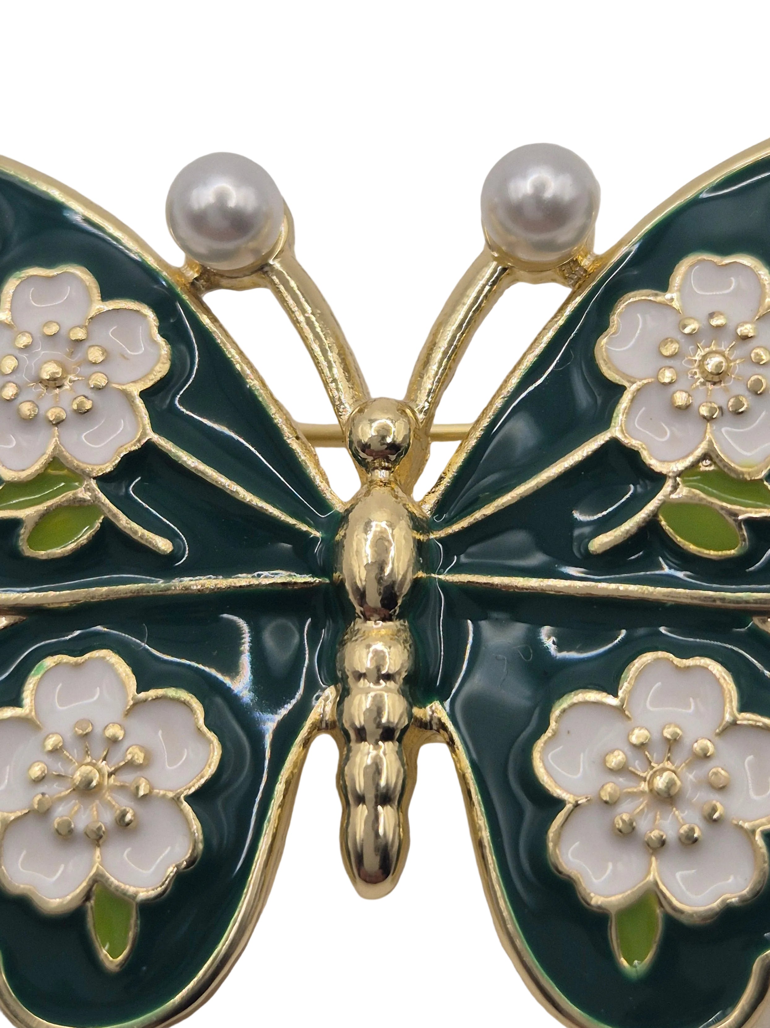 Butterfly brooch with floral and pearls detail on a white background