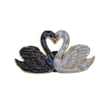 A twin swan enamel lapel pin featuring one black swan and one white swan facing each other to form a heart shape with their necks, outlined in gold-tone metal.