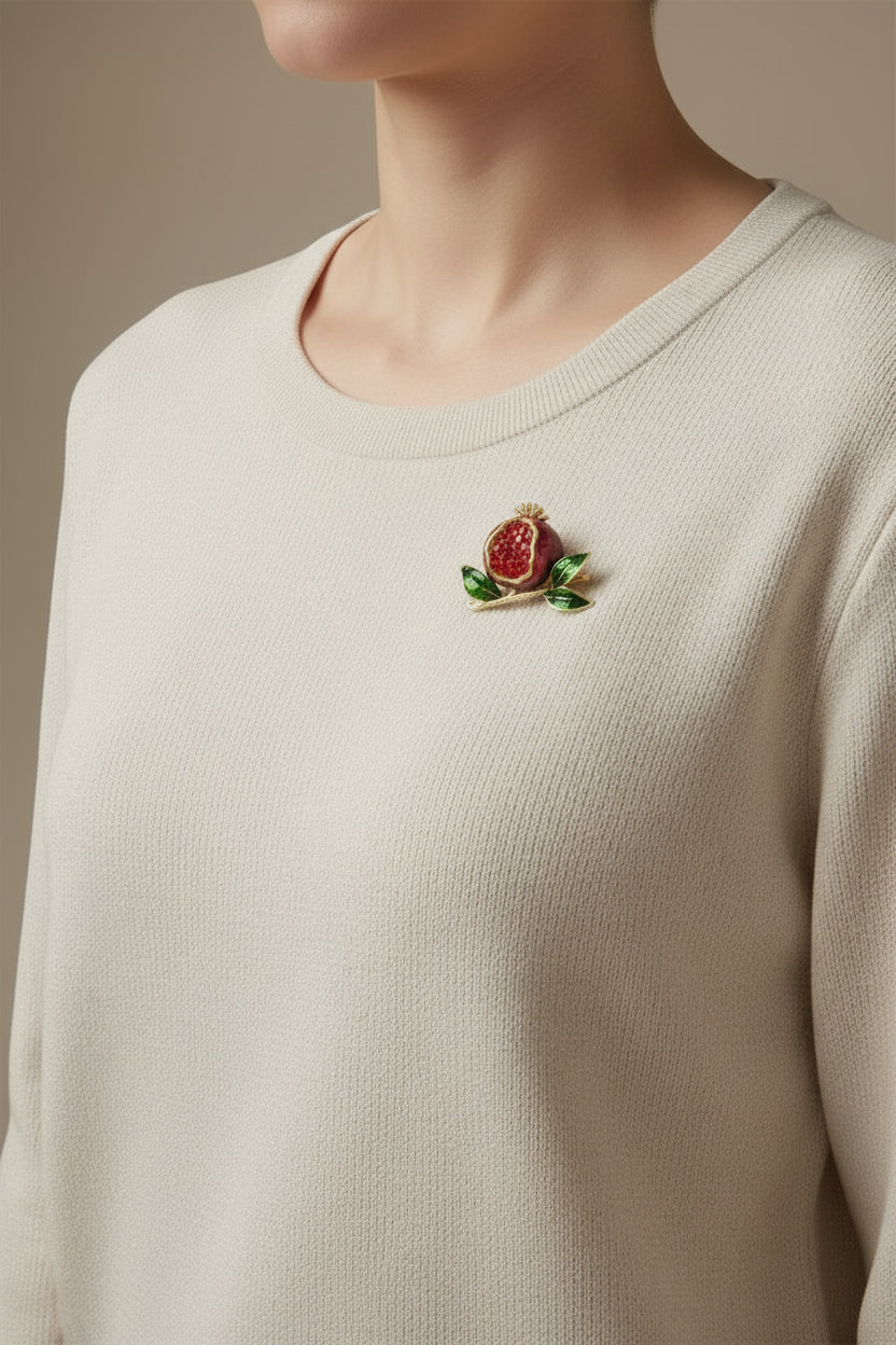 Pomegranate brooch with green leaves on a white background