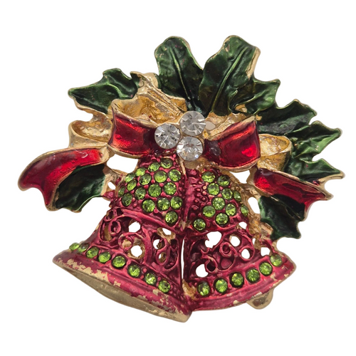 A vintage-style Christmas holly and bell brooch featuring red enamel, green enamel, gold-tone metal, and clear rhinestones on a white background.
