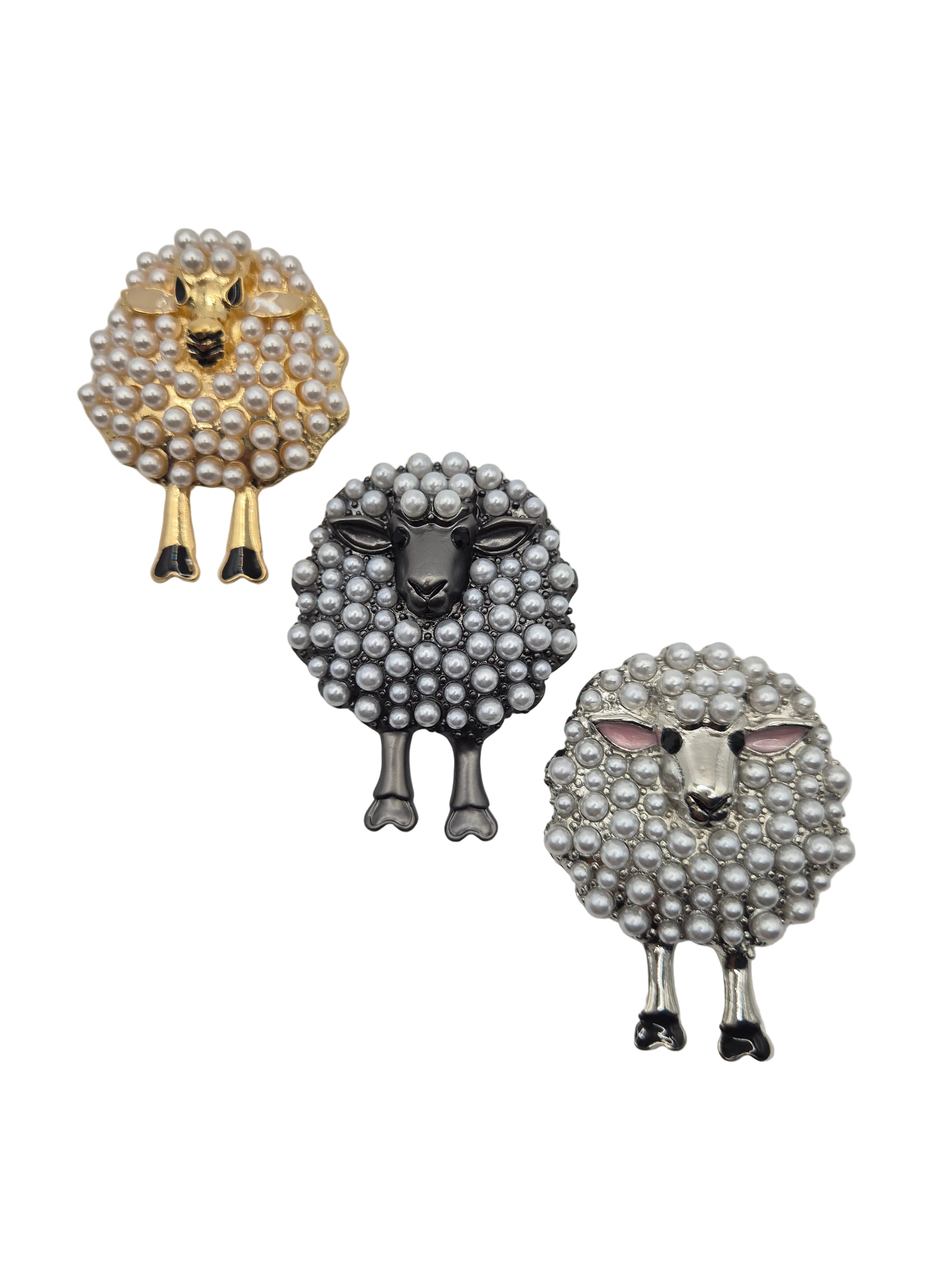 Three sheep-shaped brooches with pearl detailing on a white background