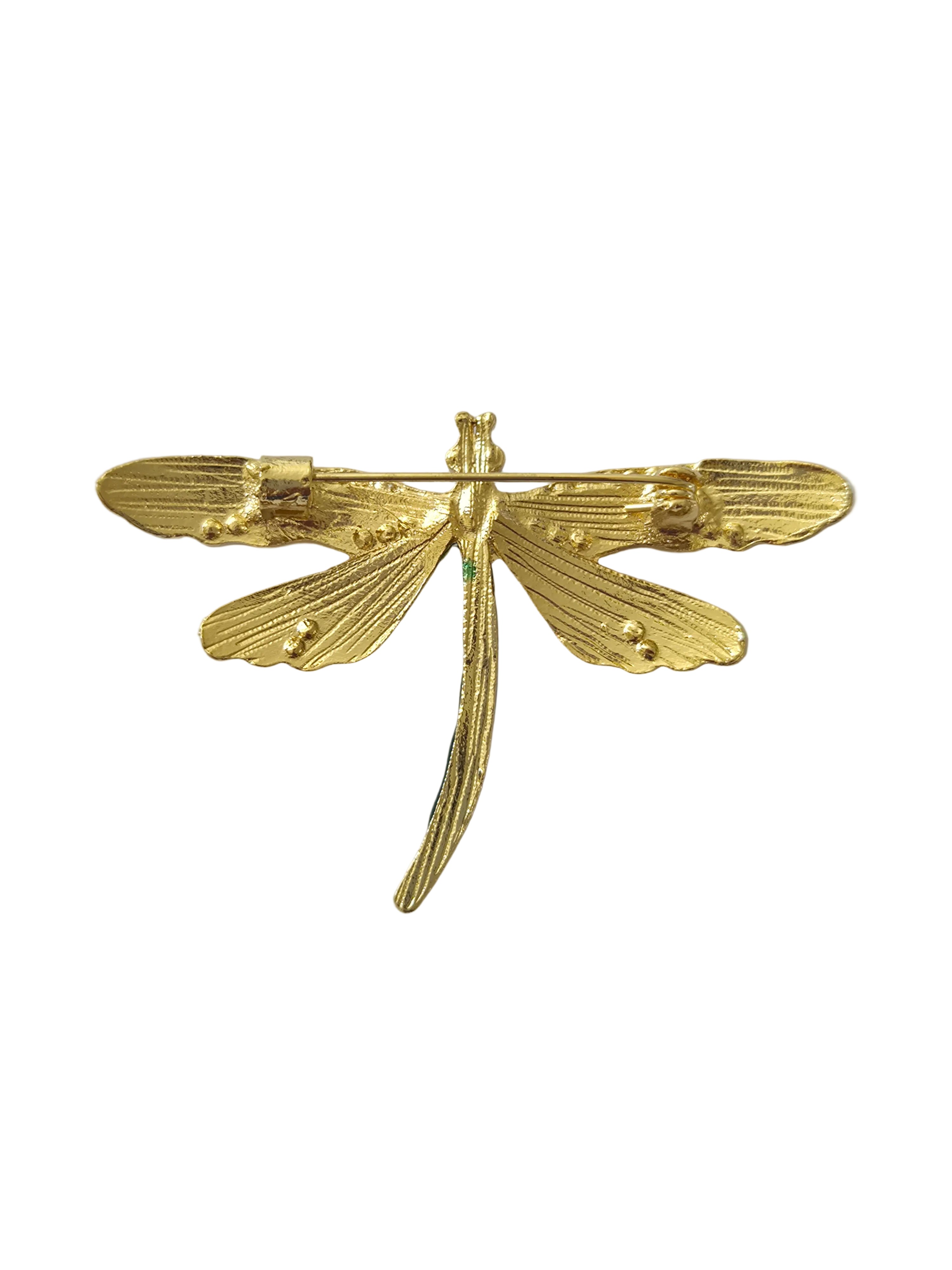 Gold dragonfly-shaped brooch on a light gray background