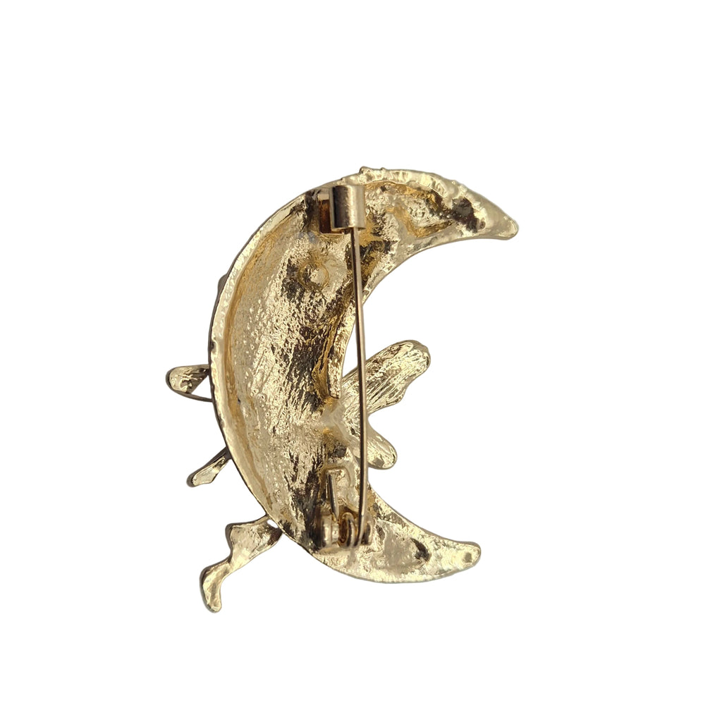 A gold crescent moon pin with textured metallic detailing and a visible safety pin mechanism, shown against a plain white background.