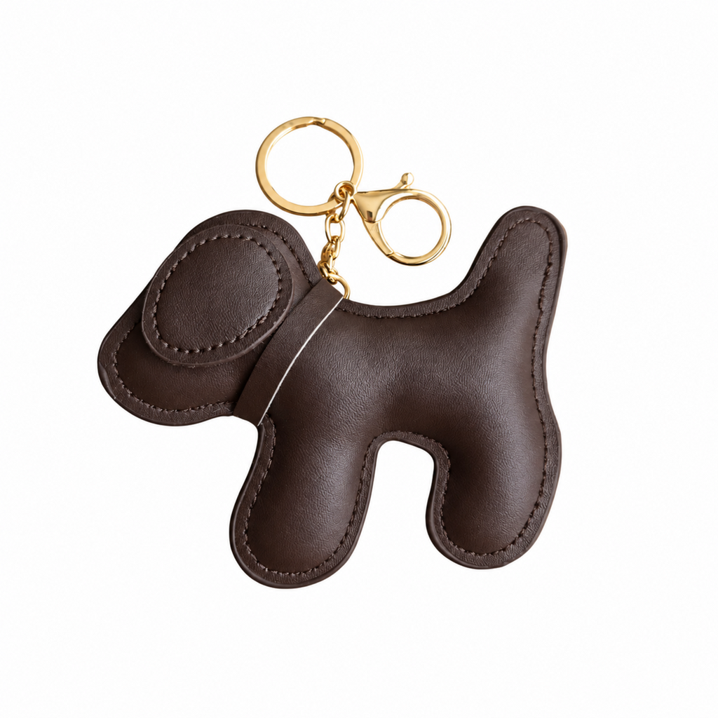 A dark brown leather dog-shaped keychain  bag charm with gold-tone metal hardware, shown on a plain white background.