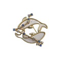 A gold-tone Pisces fish brooch with a milky white mother-of-pearl style inlay and small blue and clear rhinestone accents, shown on a plain white background.