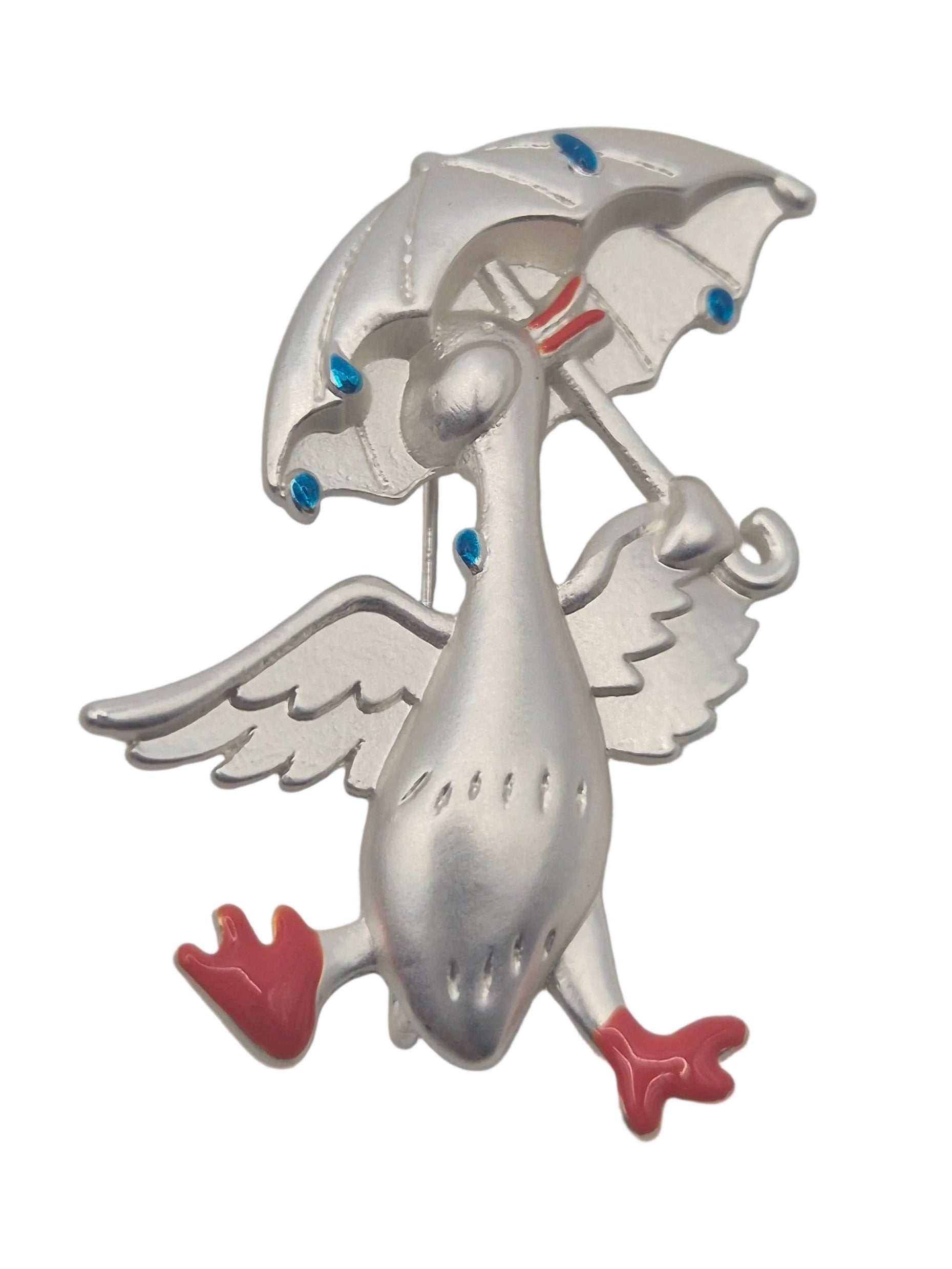 Silver tone metal duck holding an umbrella brooch with raindrops on a plain white background 
