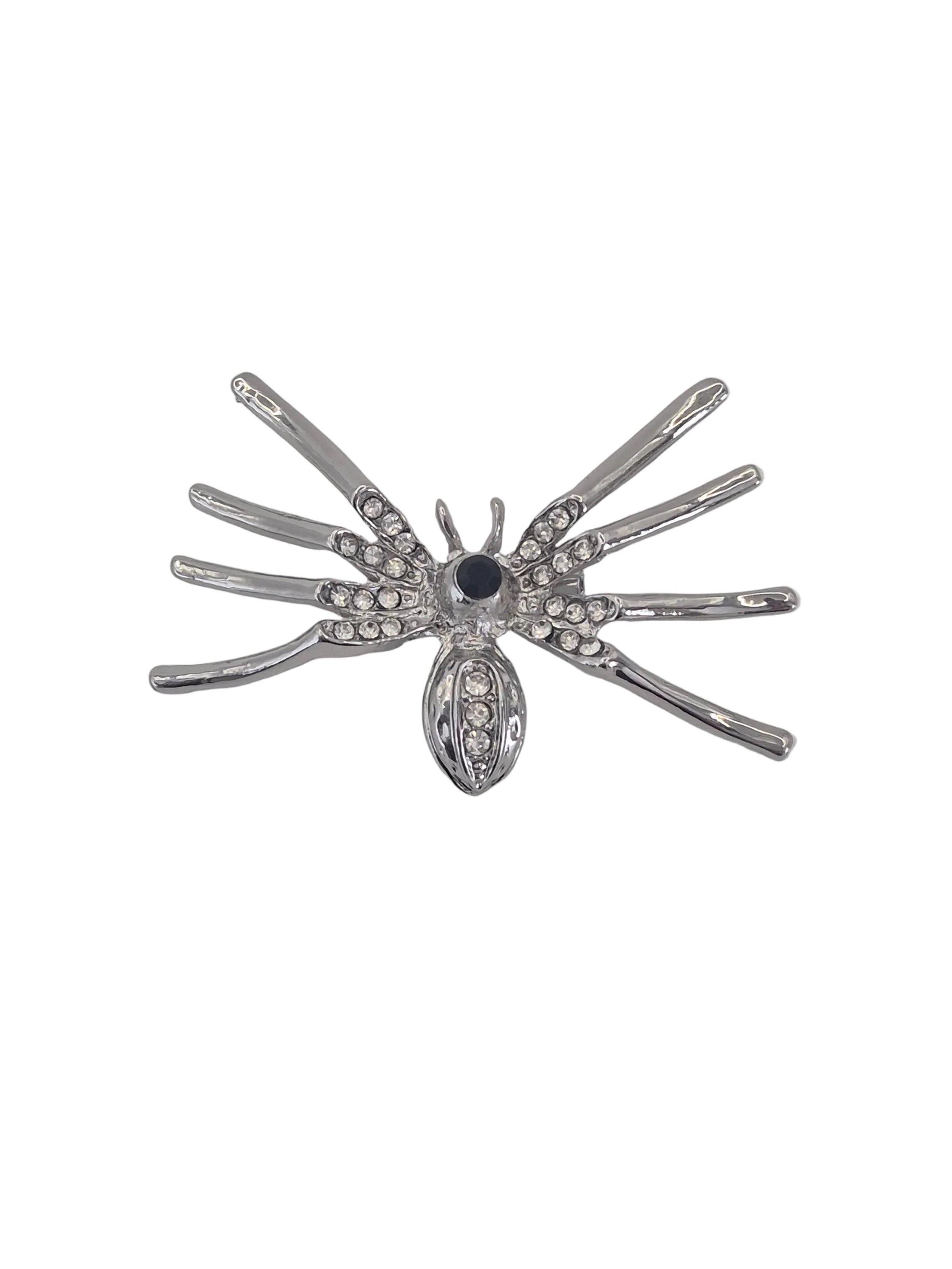 A silver spider-shaped brooch embellished with clear rhinestones and a central black stone, shown on a plain white background.
