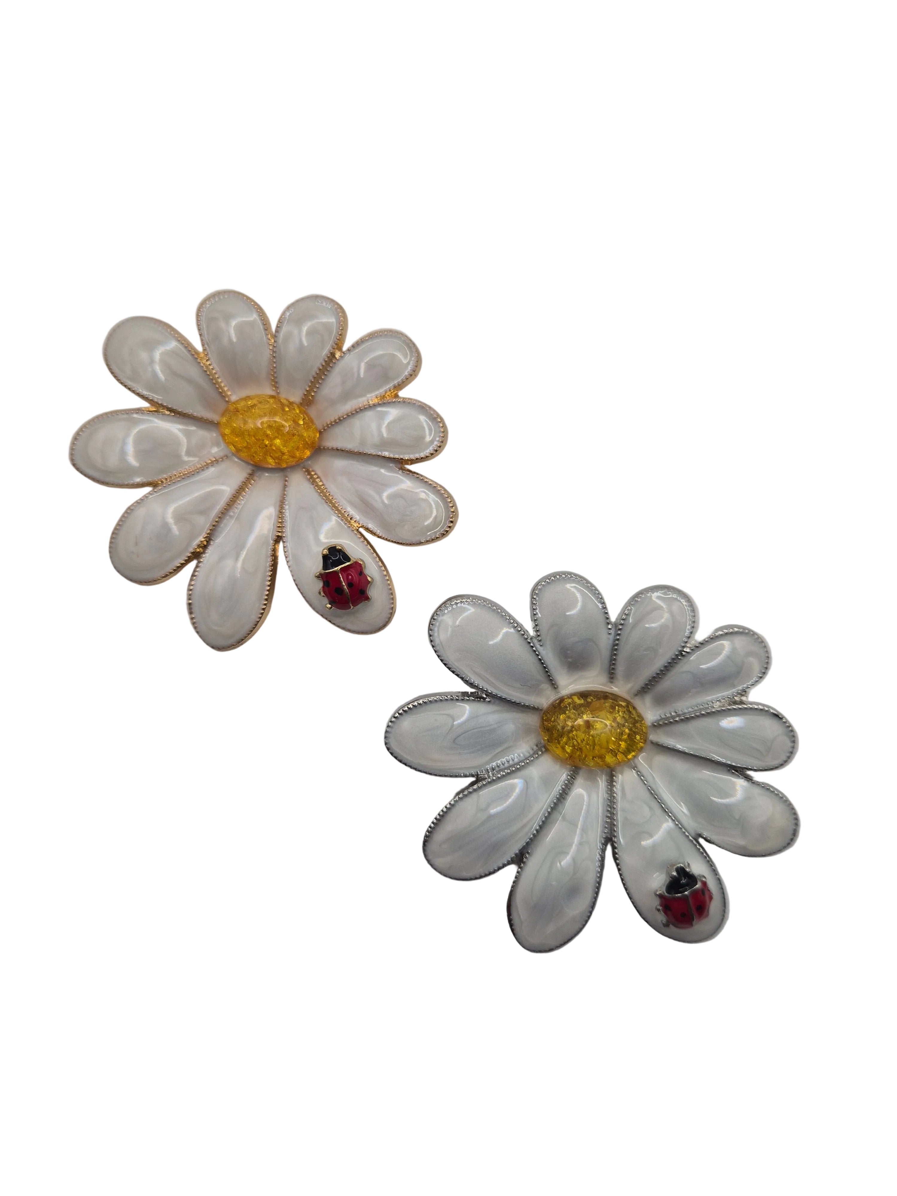 White daisy-shaped brooch with yellow centers on a white background