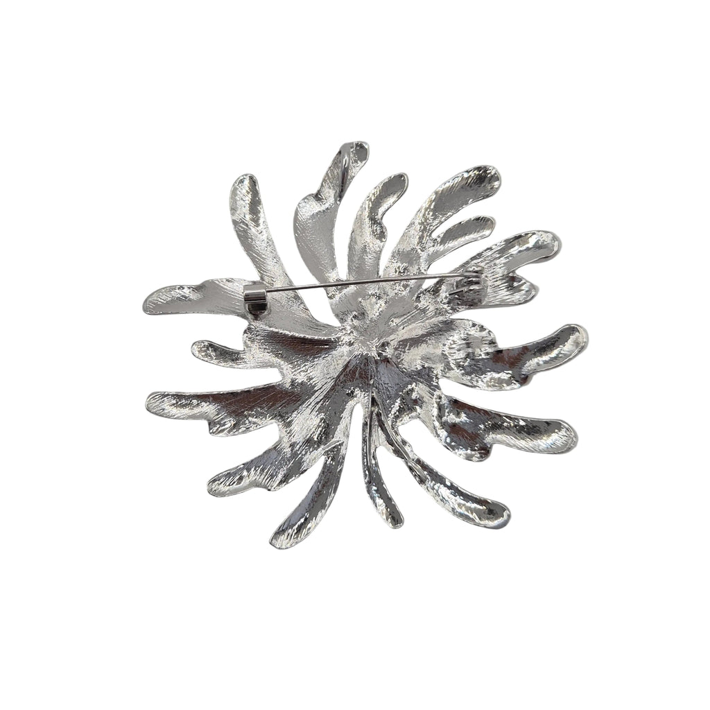 A silver toned metal firework burst brooch displayed against a plain white background.