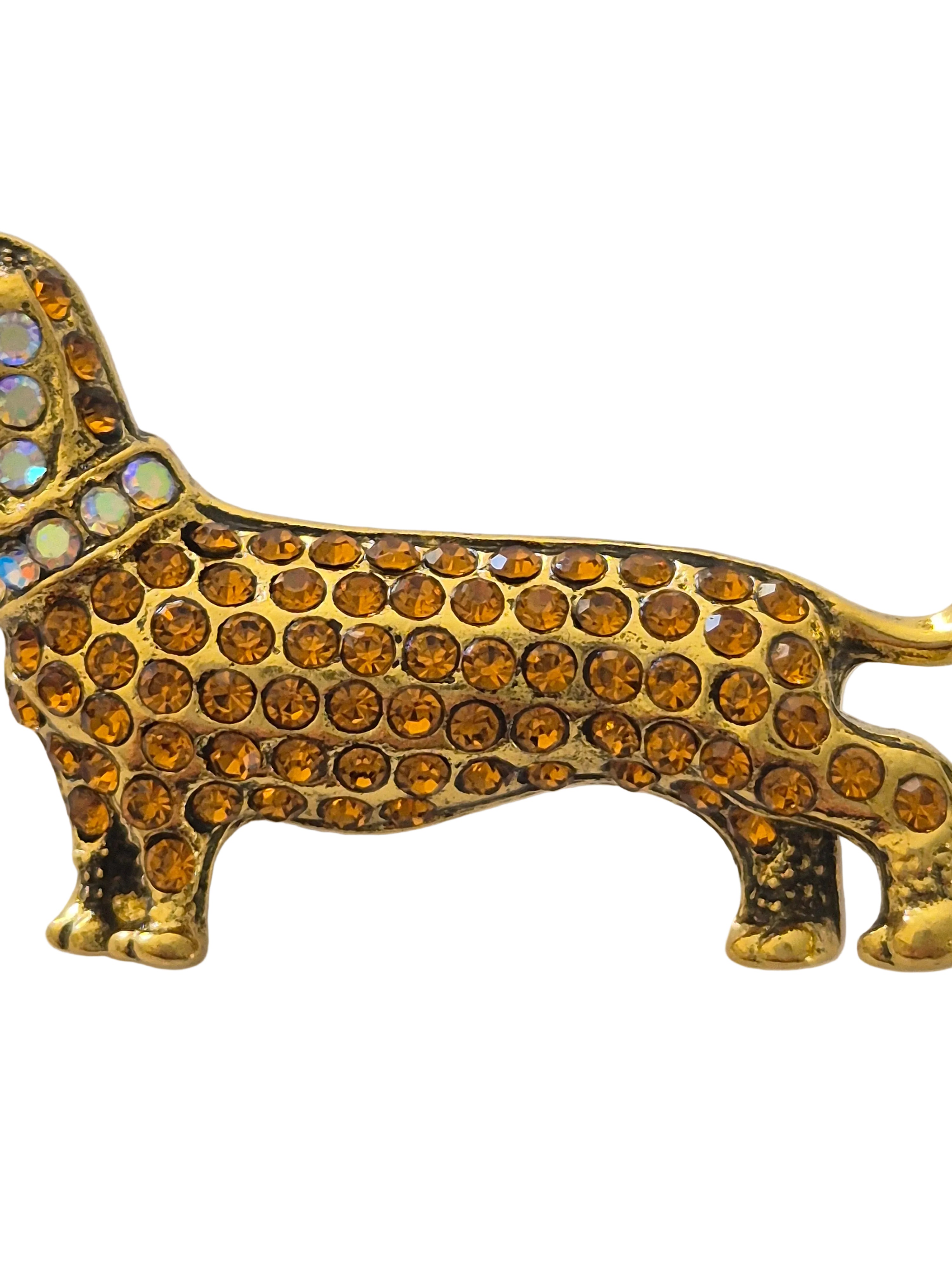 Gold dog-shaped  dachshund dog brooch with amber-colored stones on a white background