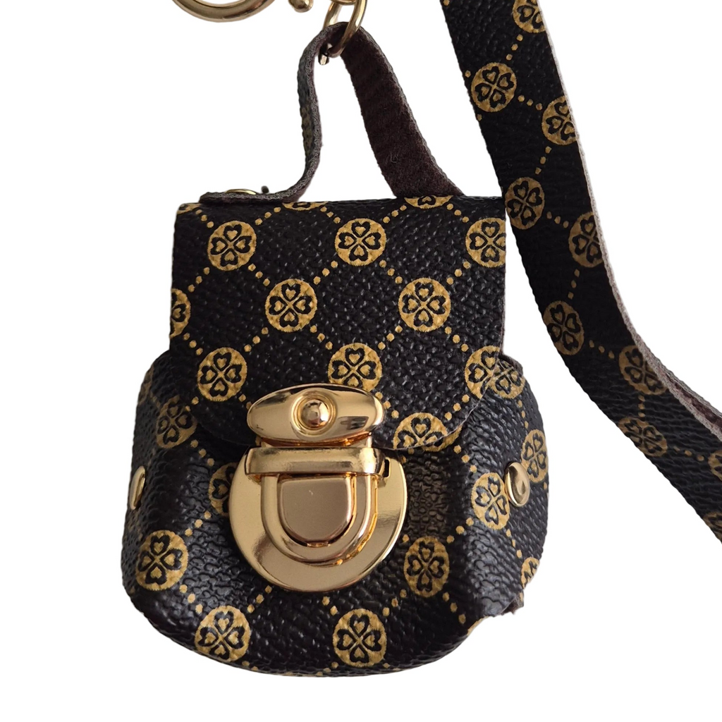 A small brown faux leather keychain bag with a gold monogram pattern and a gold clasp, shown on a white background.