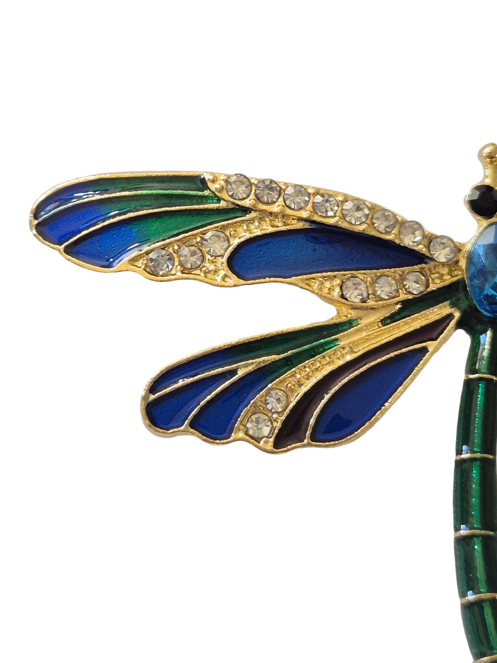 Decorative dragonfly brooch with blue and green wings and gold accents on a white background