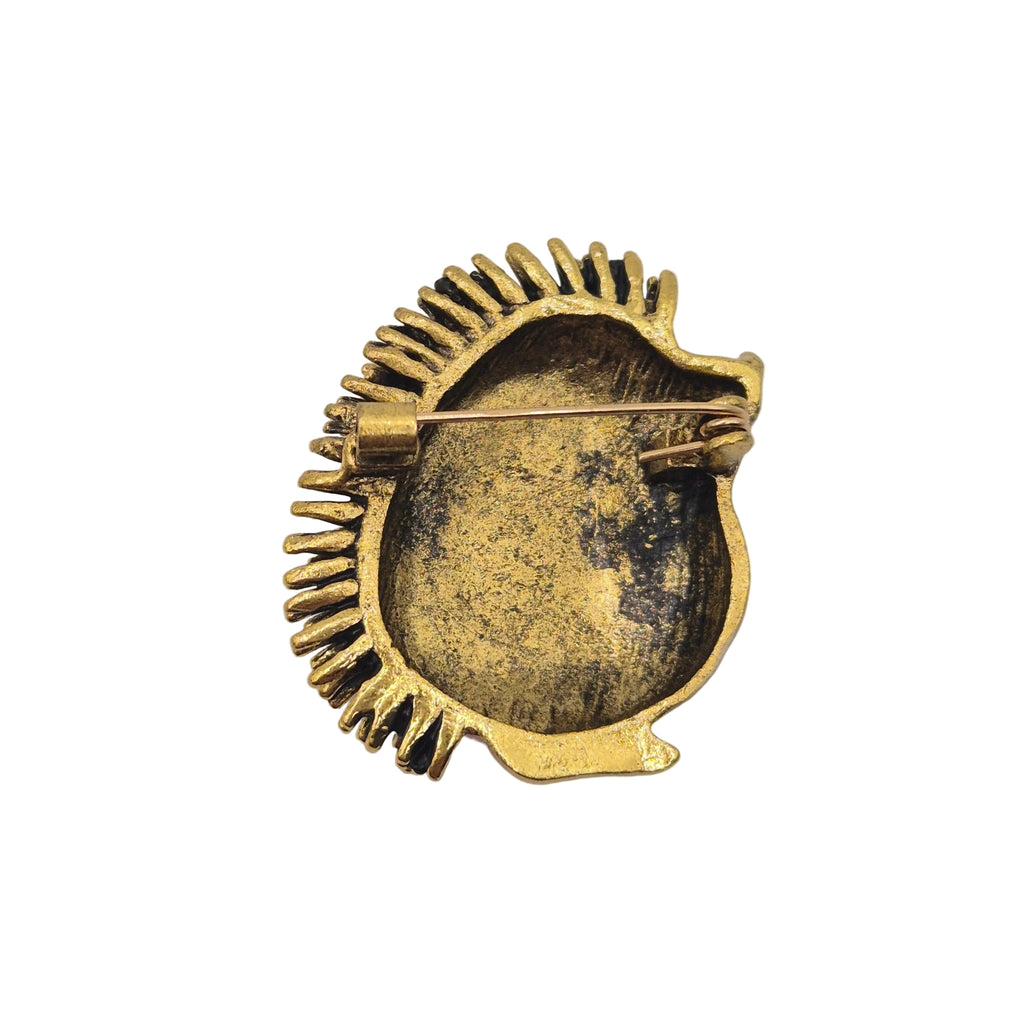 Reverse gold tone side of a hedgehog brooch pin showing the pin mechanism. Displayed against a plain white background.