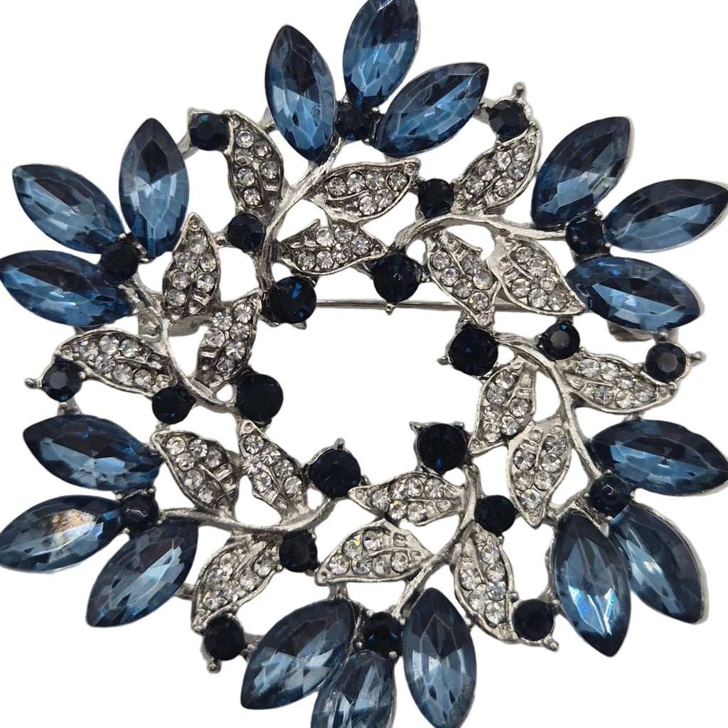 Blue and silver wreath brooch on white background with rhinestones