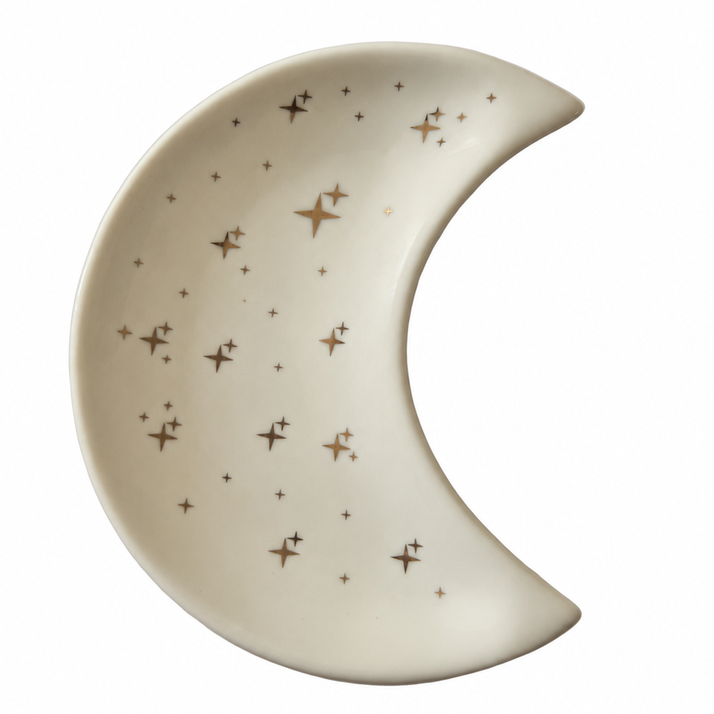A crescent moon-shaped ceramic plate or dish in warm off-white, decorated with a scattered pattern of metallic gold stars of varying sizes, shown on a plain white background.