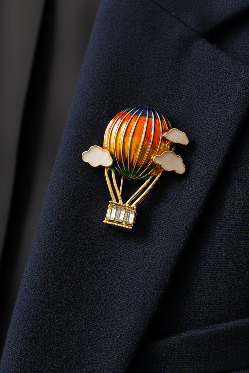Colorful hot air balloon brooch with gold accents on a light gray background